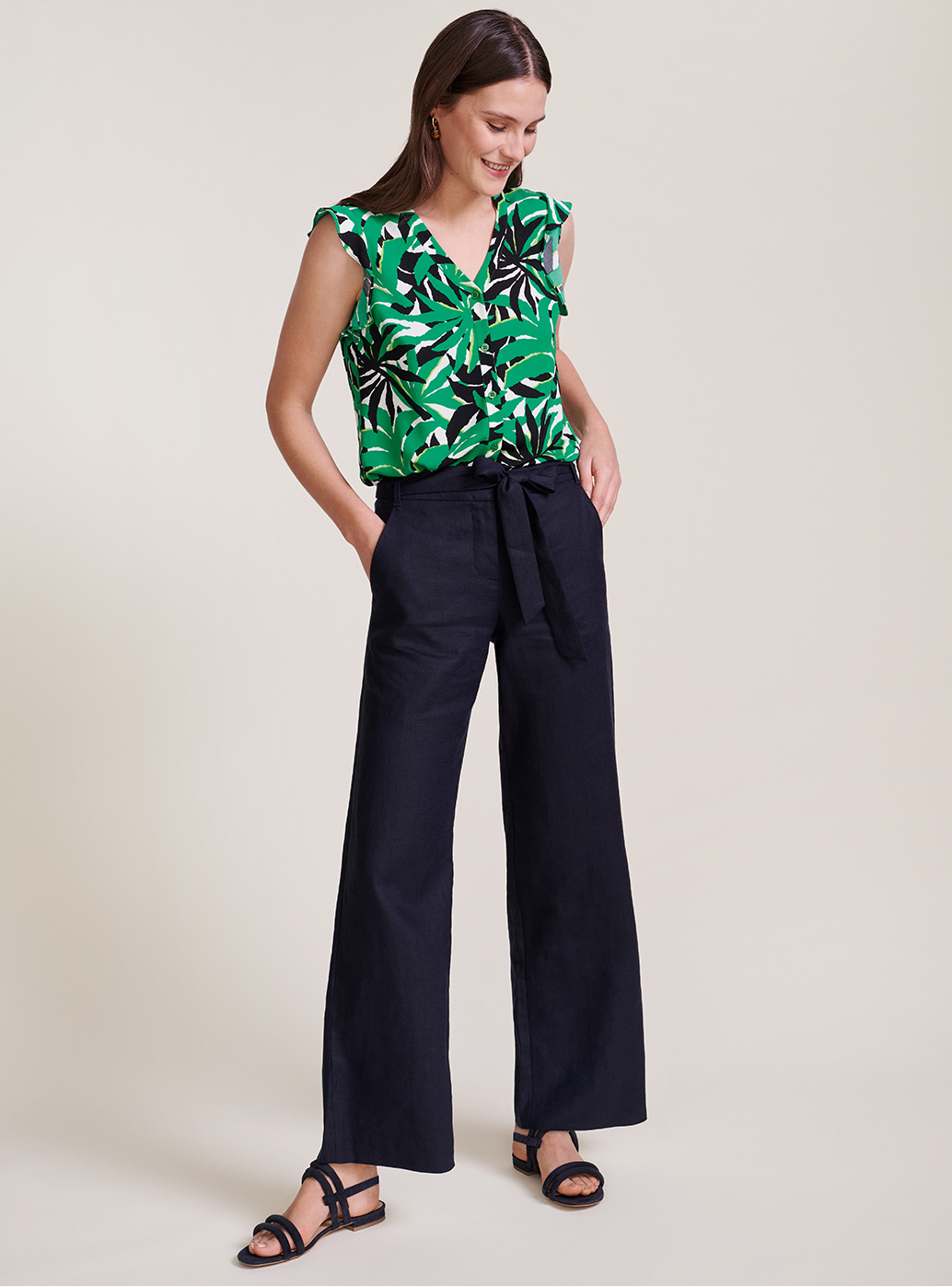 Model wears a jungle print blouse, tucked into wide leg linen trousers. 