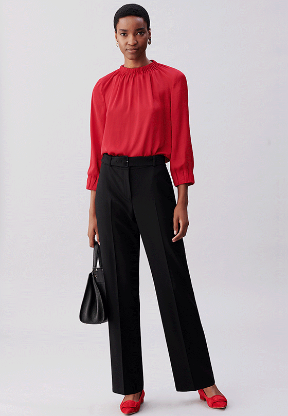 Full length image of model wearing a Hobbs red blouse with black trousers.