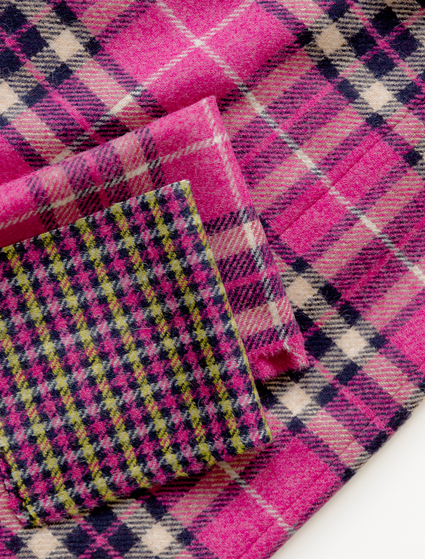 Alt text: Close up shot of pink wool fabric with check patterns from Abraham Moon, a British woollen mill.
