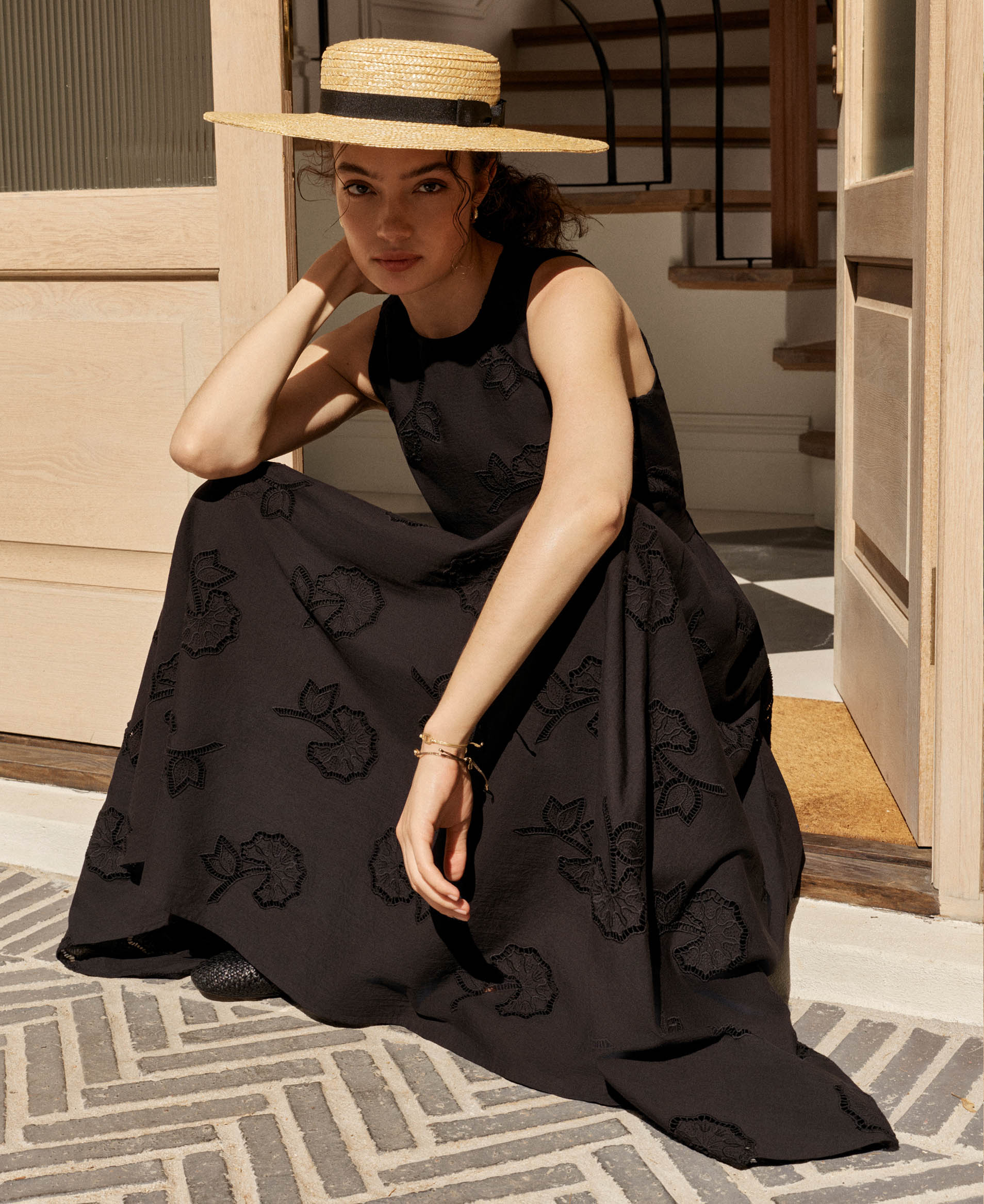 A woman wearing an embroidered, black, maxi dress.
