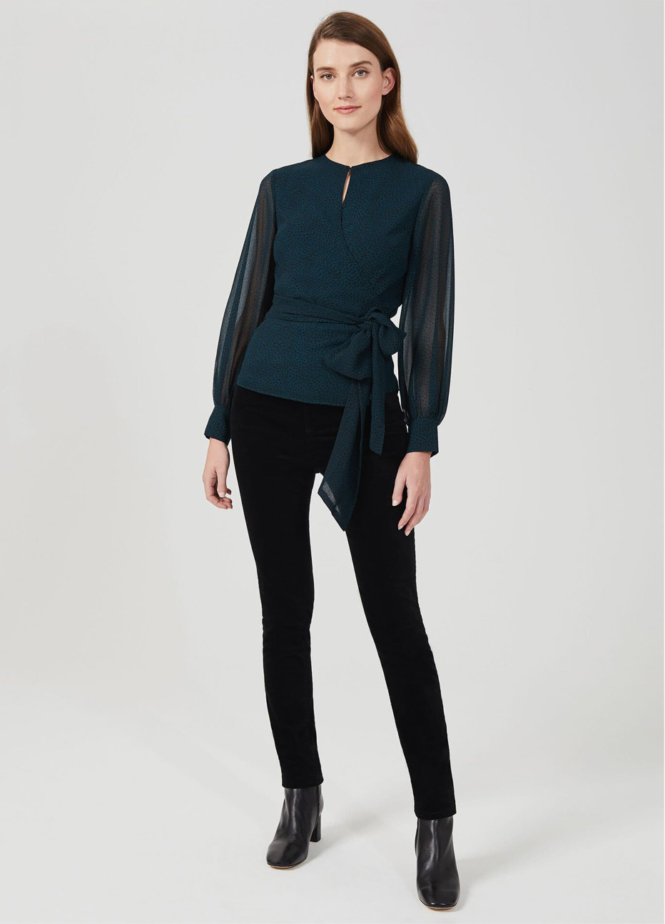 Hobbs model wearing a wrap blouse with sheer sleeves, styled with black fitted jeans and black leather boots.
