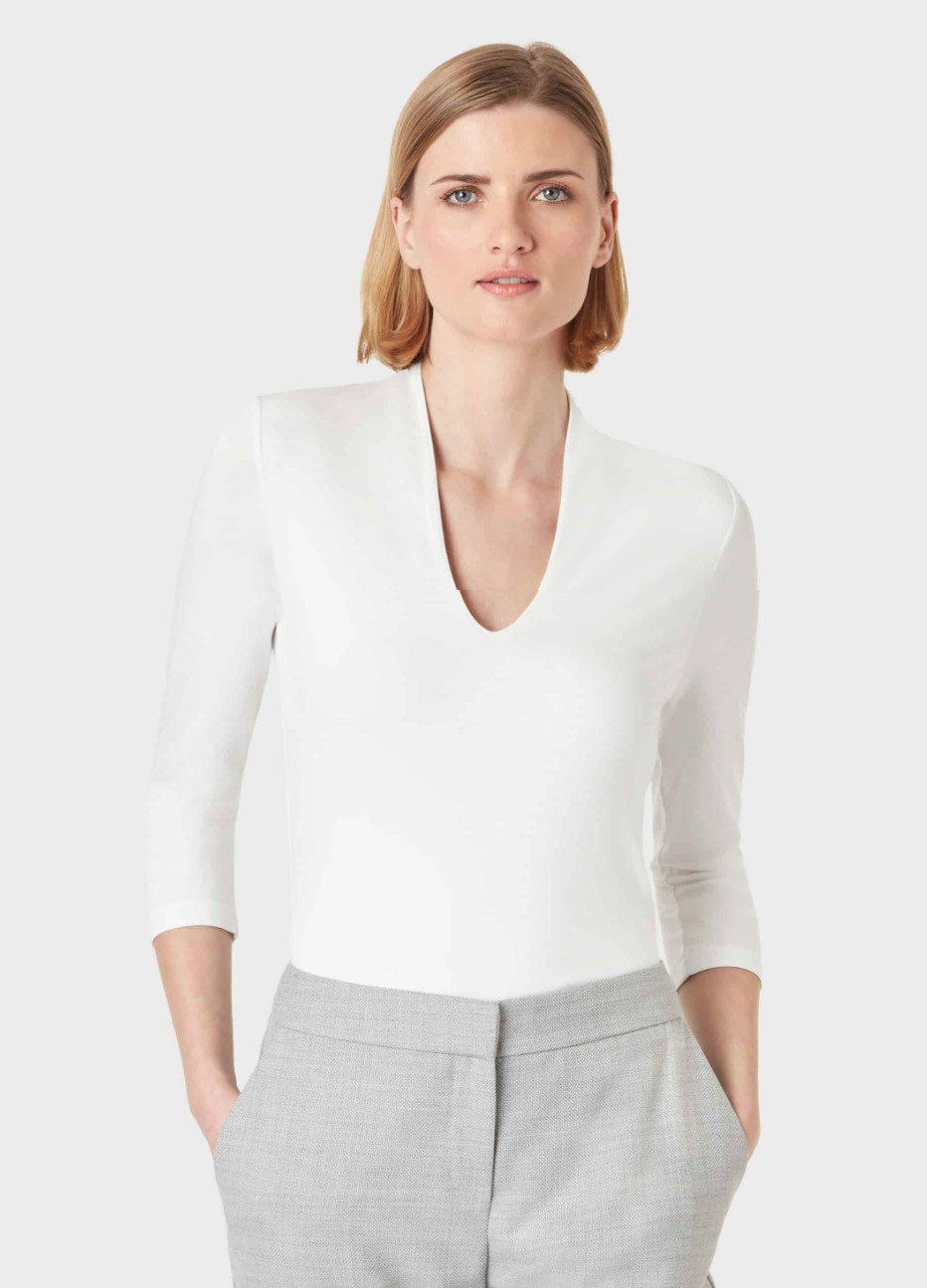 White v neck jersey top worn with grey tailored trousers by Hobbs.