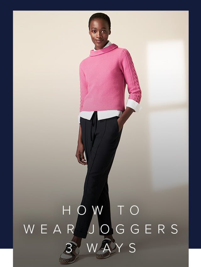 Model photographed wearing a pink knitted jumper with navy joggers and trainers.