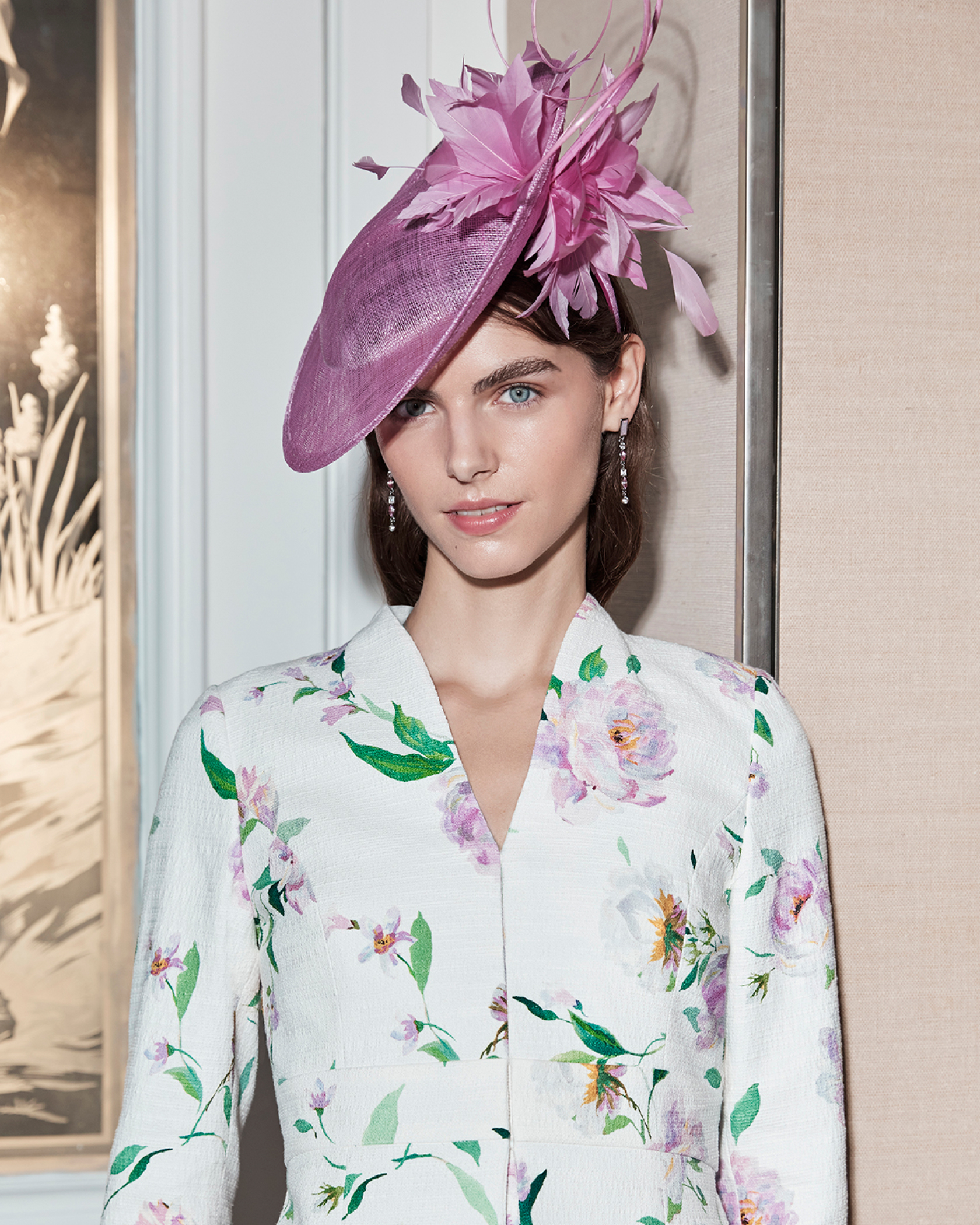 Hobbs model wears a floral two-piece suit and pink fascinator.