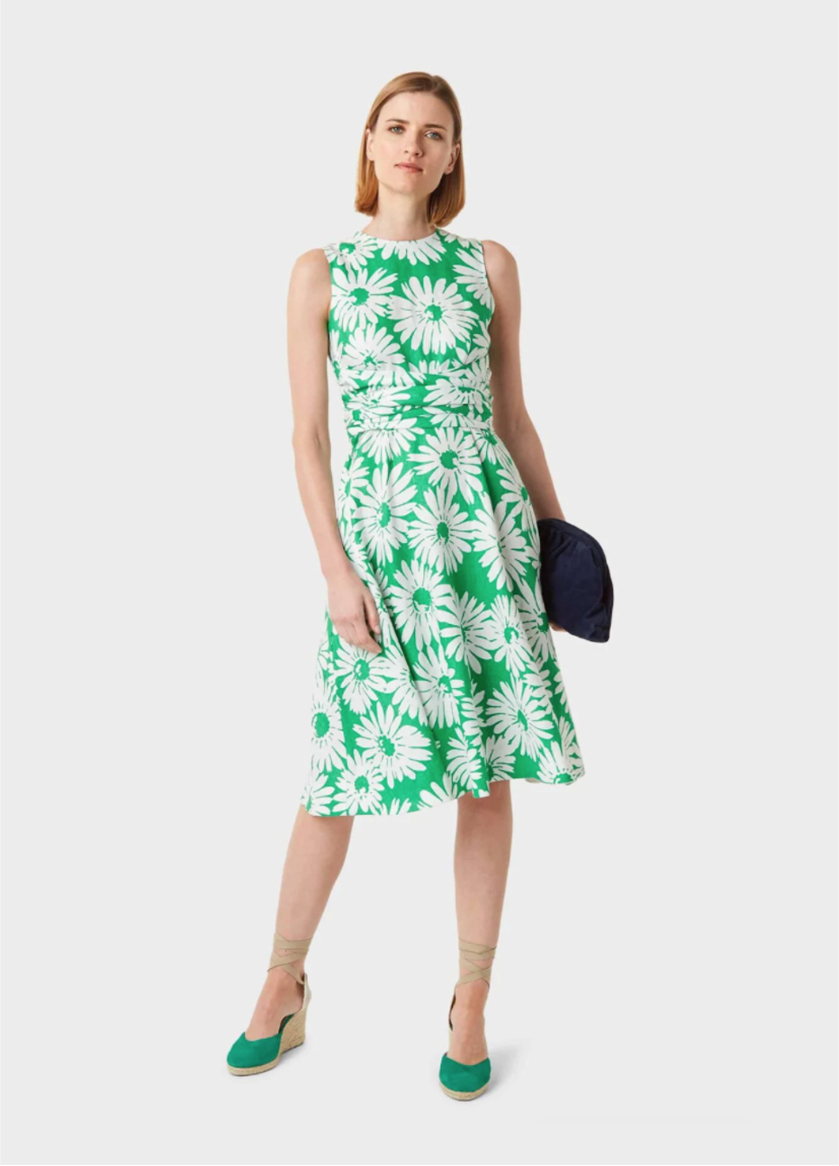 Green fit and flare shift dress with a floral pattern paired with wedge espadrilles in green and a black clutch bag, by Hobbs.