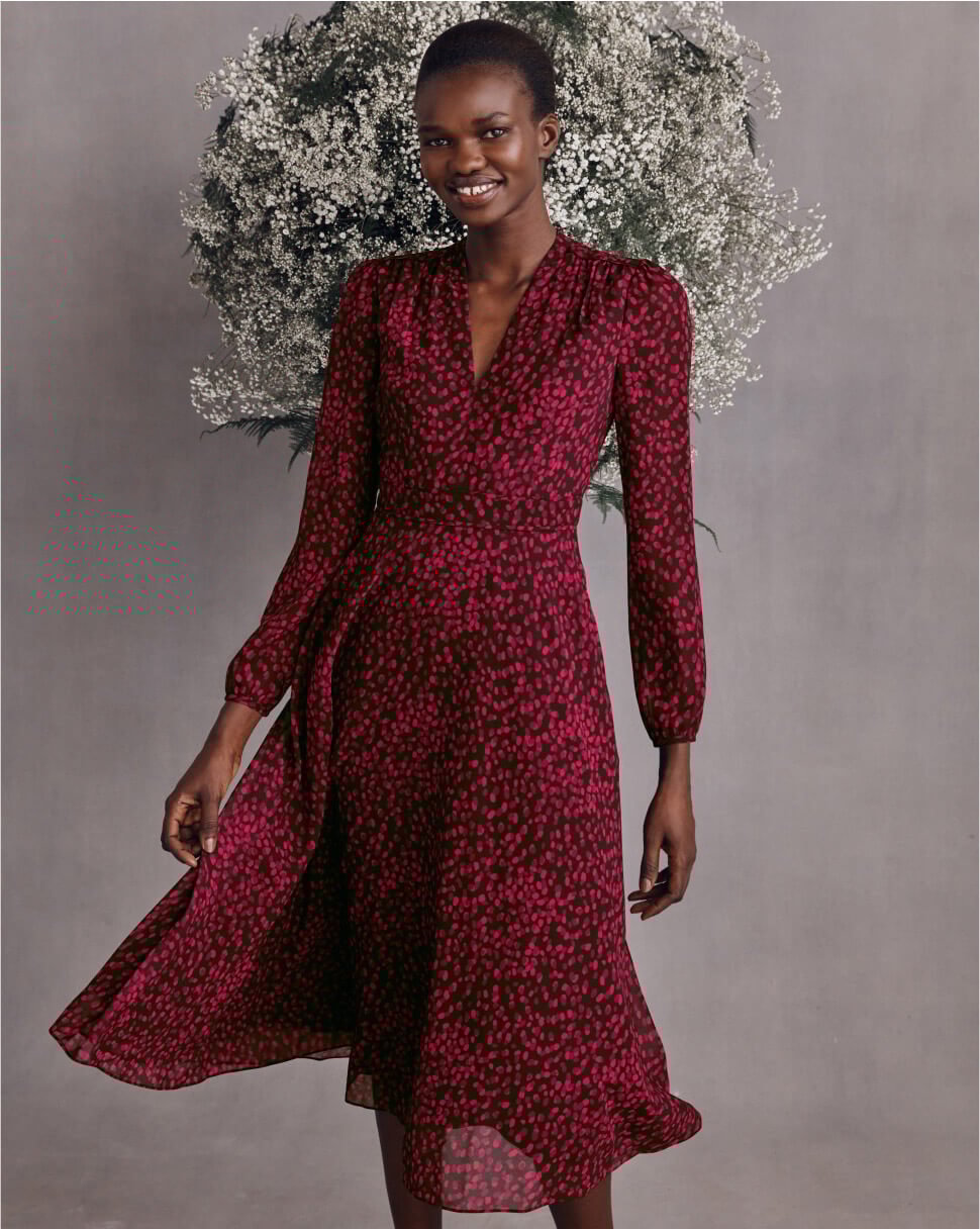 A burgundy suede court shoe and clutch bag sit atop a marble plinth