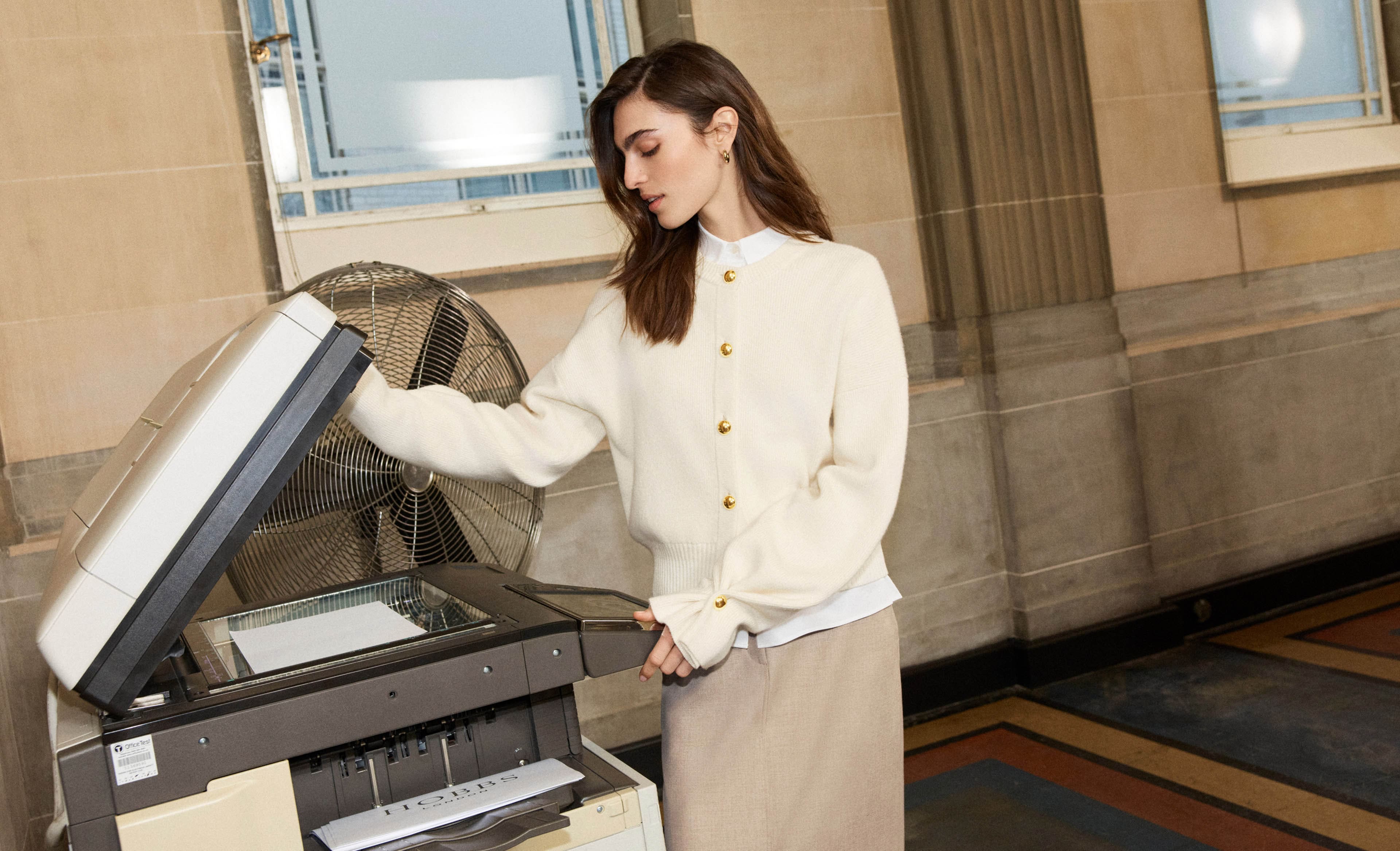A woman using a printer wearing Hobbs' new workwear collection.