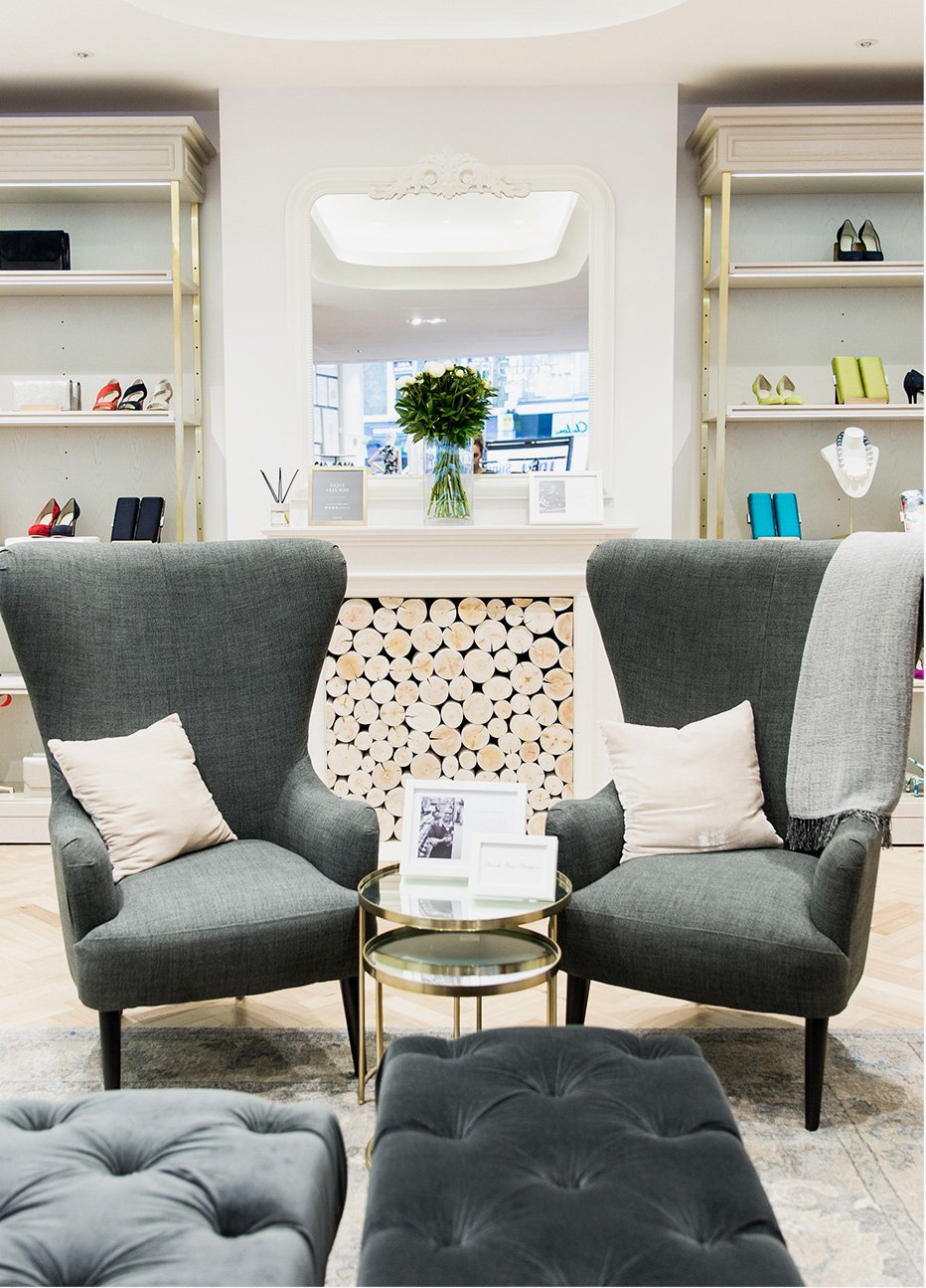 A bright interior store shot featuring two grey wingback armchairs