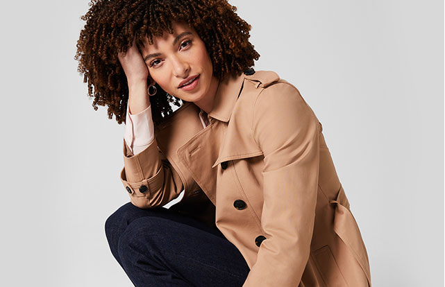 Model photographed in a crouched position wearing Hobbs camel Saskia trench.
