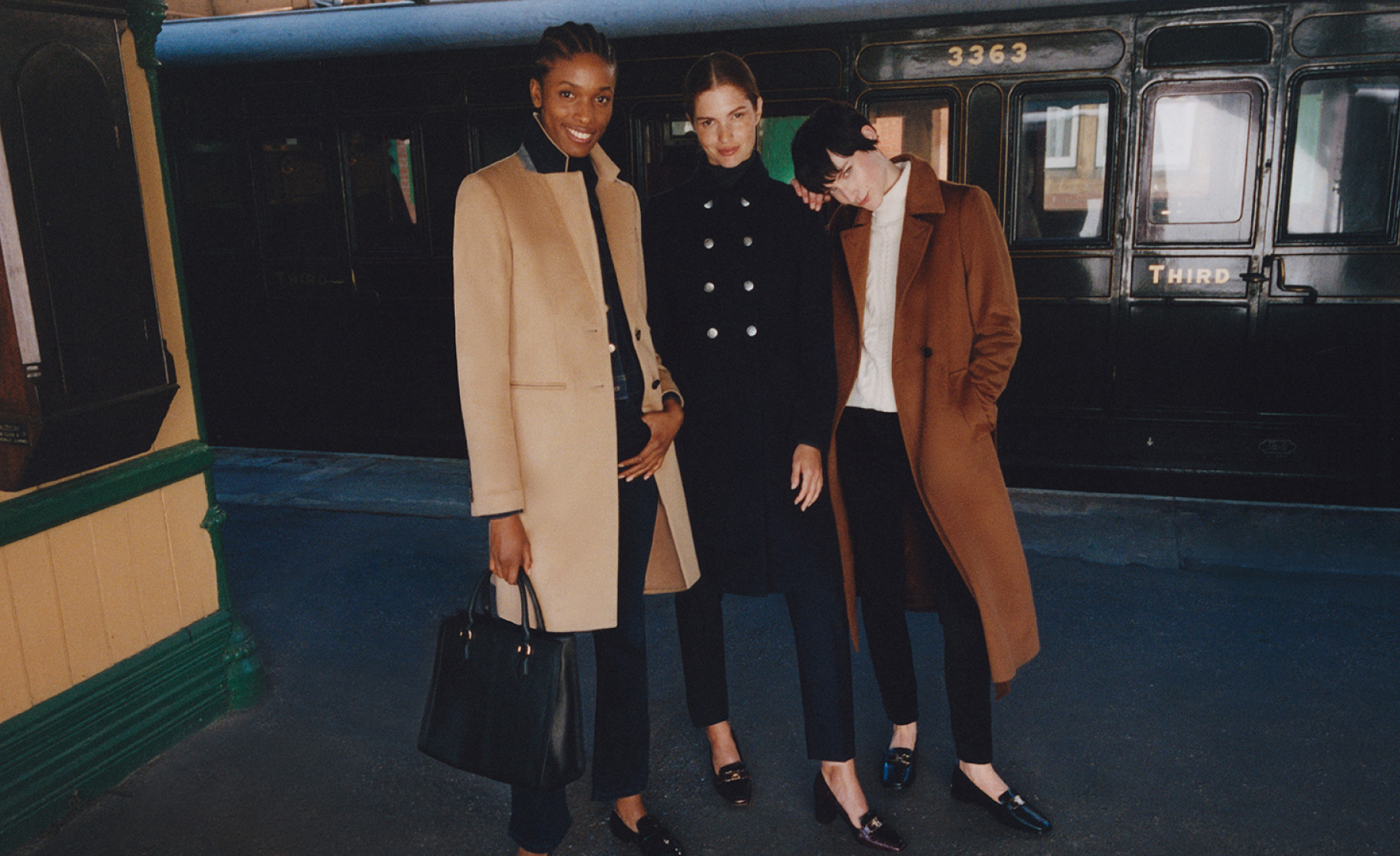 Three models photographed on a station platform wearing Hobbs wool coats.