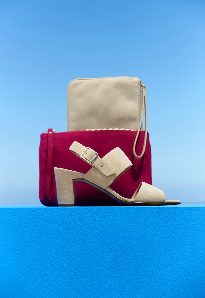 Architectural grouping of a cream and bright pink suede clutch bag with matching cream suede heeled sandals.