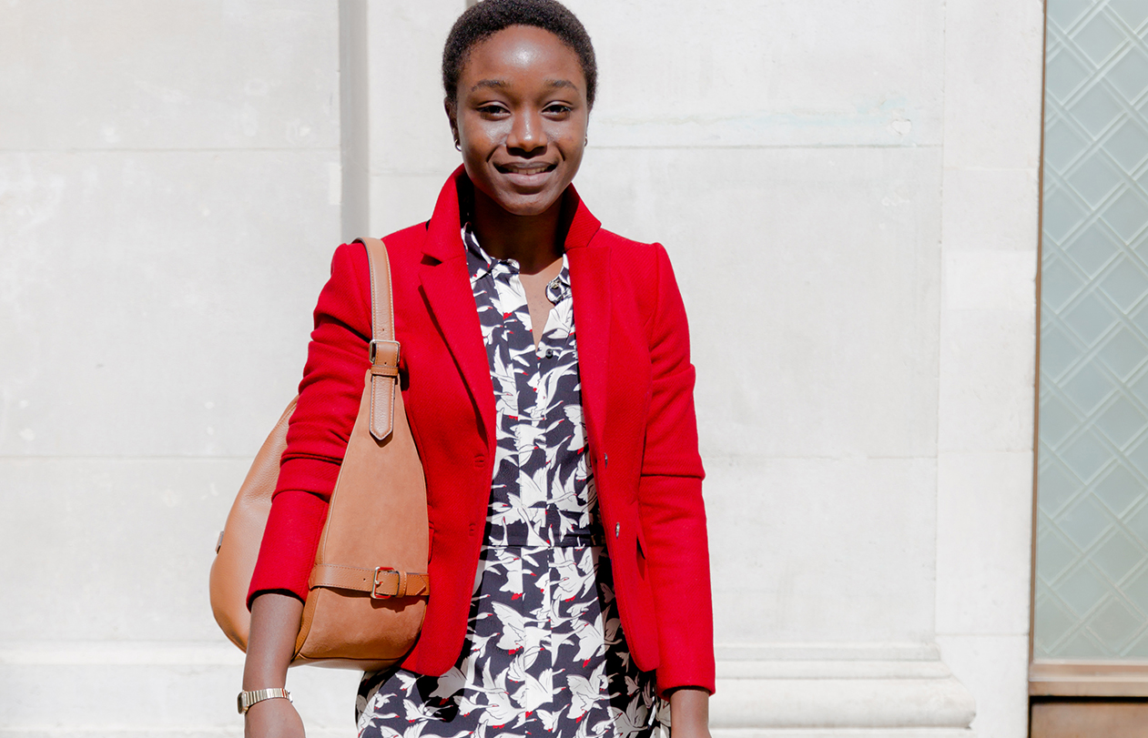 Model photographed wearing a green satin blouse with black trousers and a clutch bag from Hobbs.