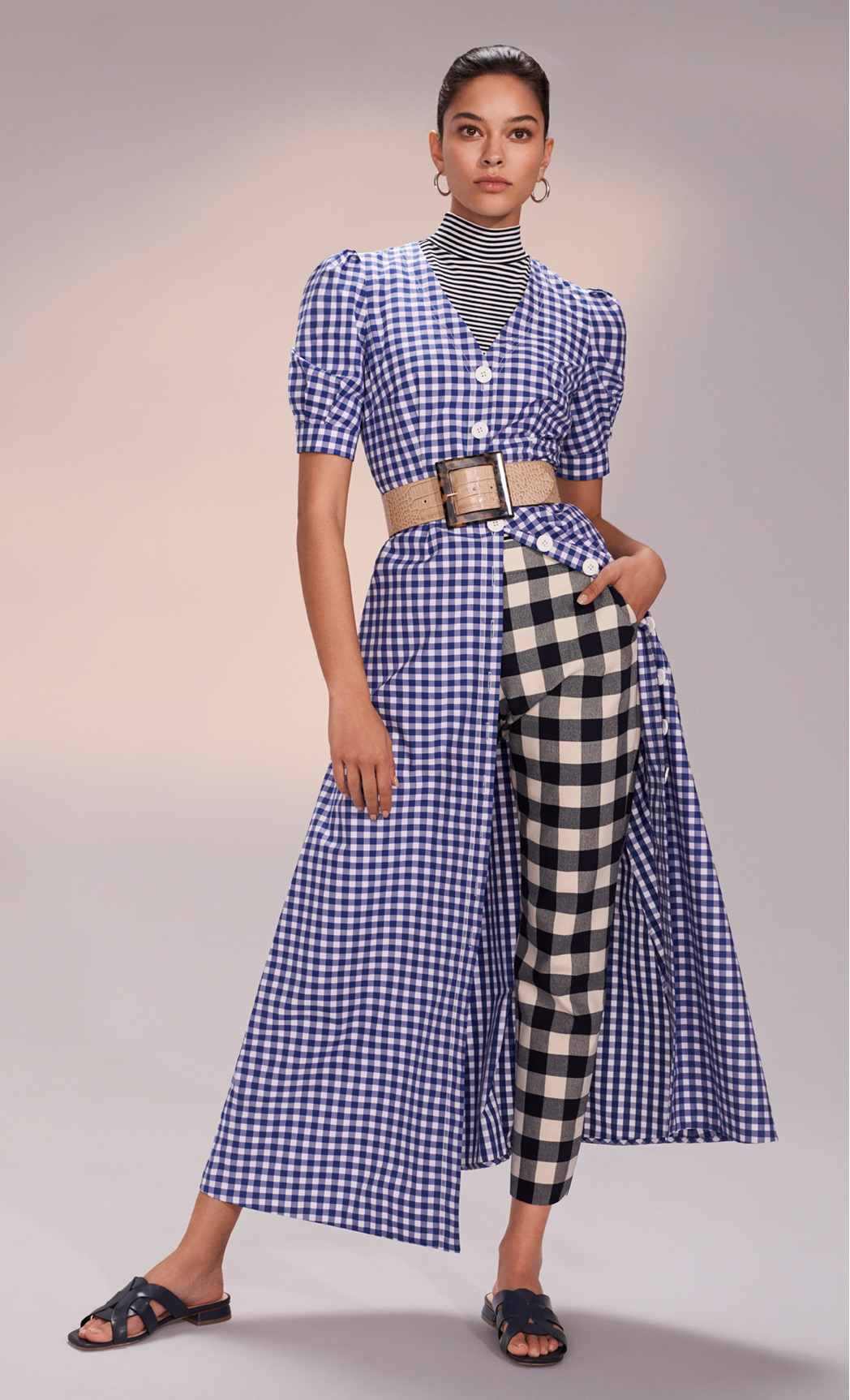 Model poses in blue gingham midi dress styled with trousers and navy sandals