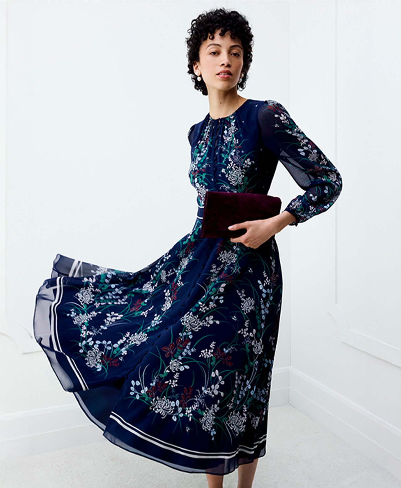 A woman wearing a navy, floral, Hobbs occasion dress.