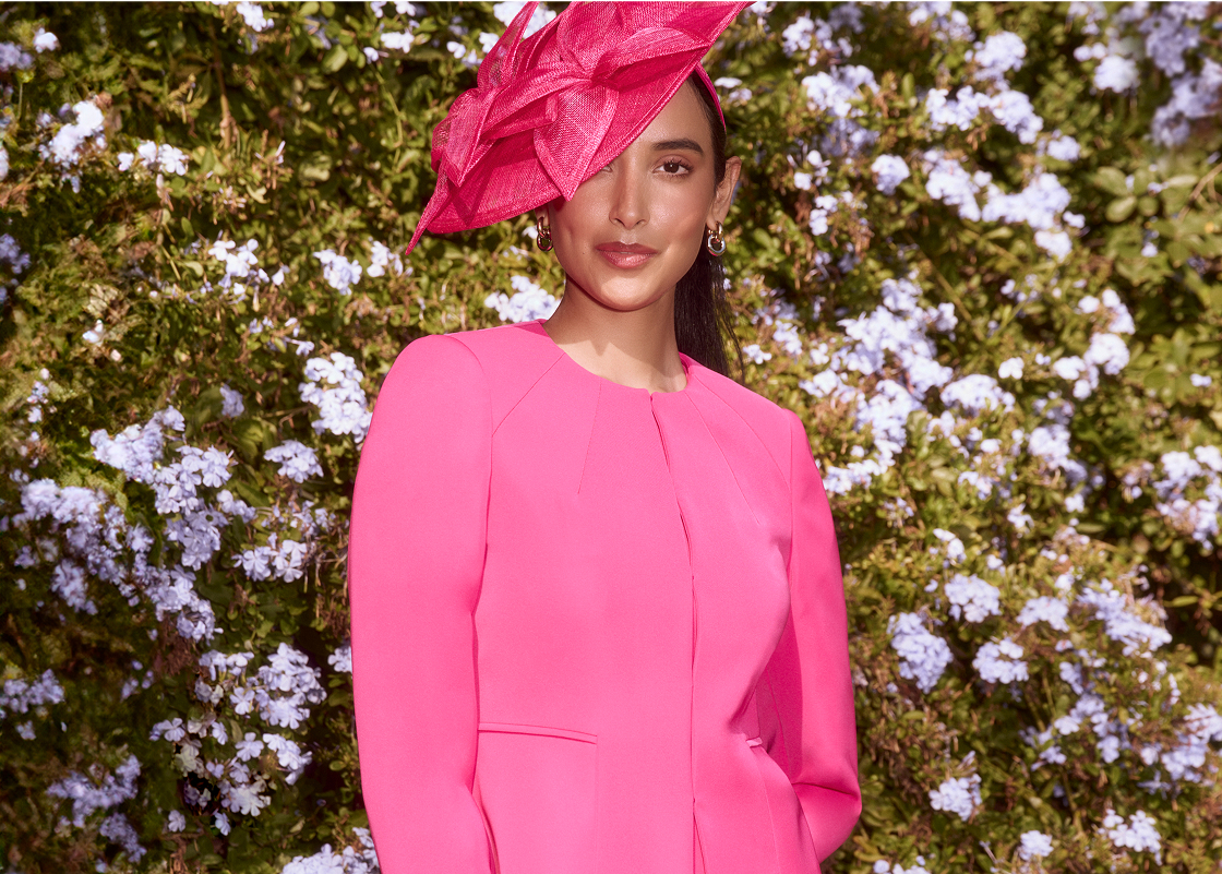 An image of a model wearing a Hobbs pink occasion jacket, dress and fascinator. 