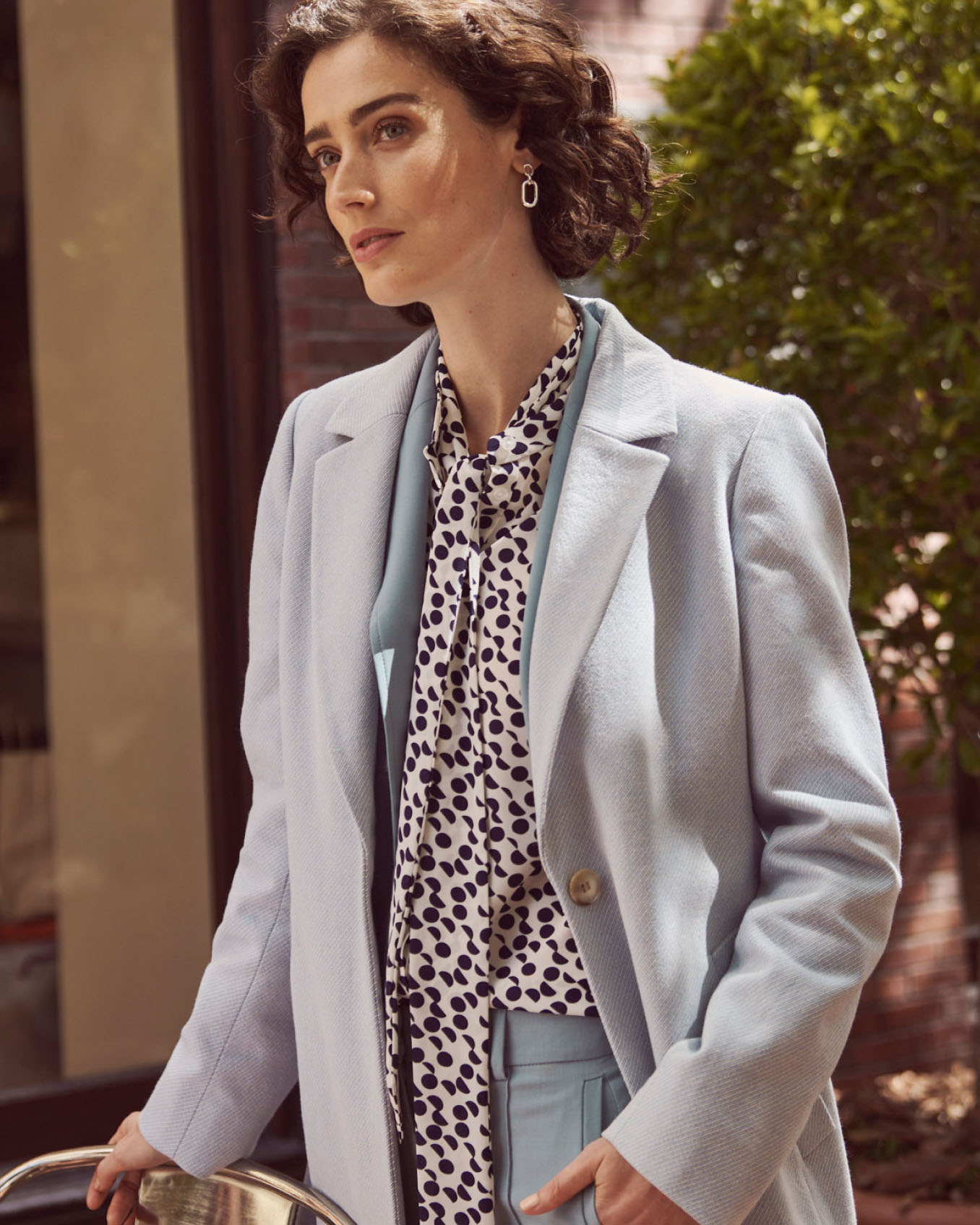 Hobbs model wears a tailored coat over a trouser suit.