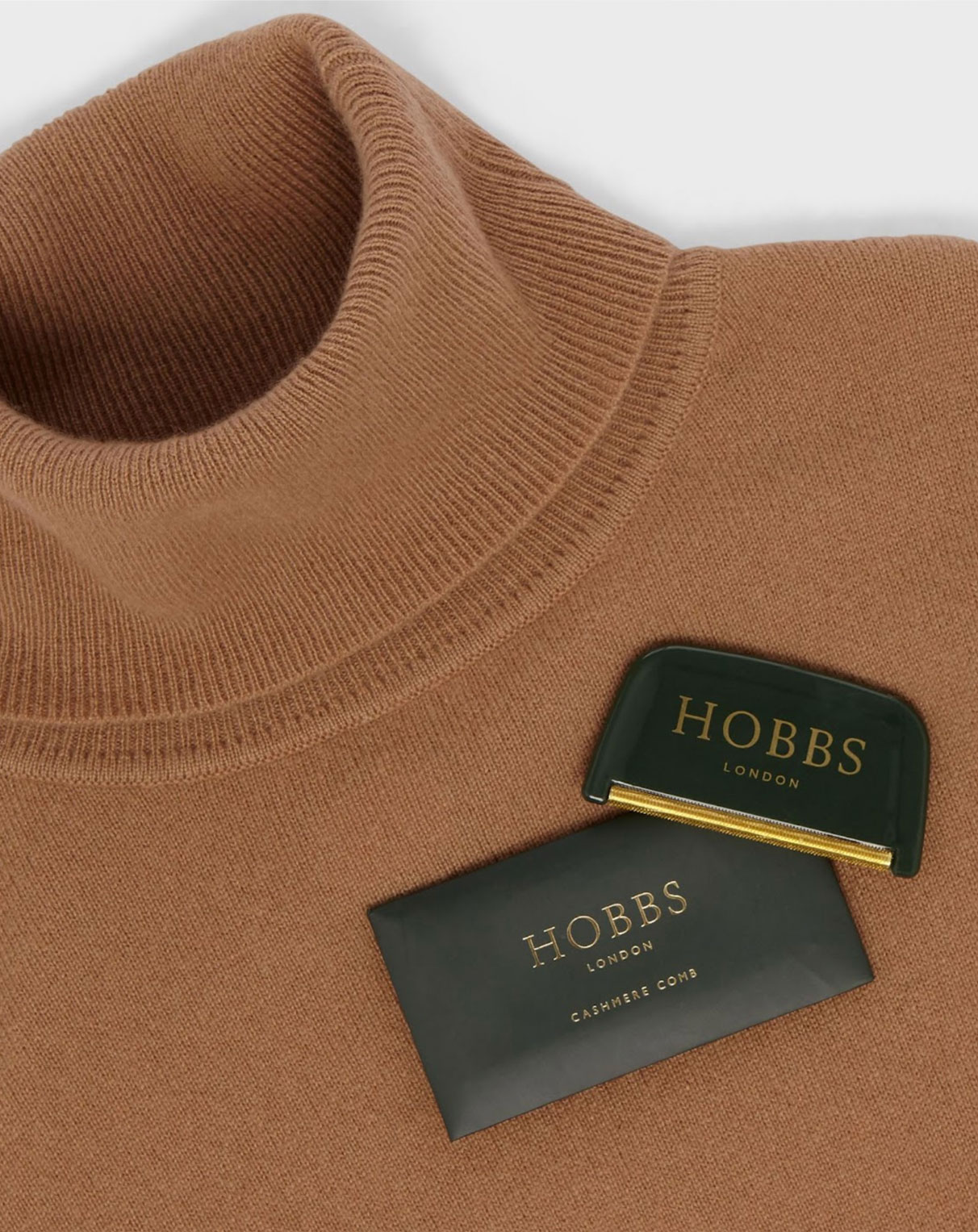 A Hobbs cashmere comb sits on top of a camel cashmere roll neck jumper.