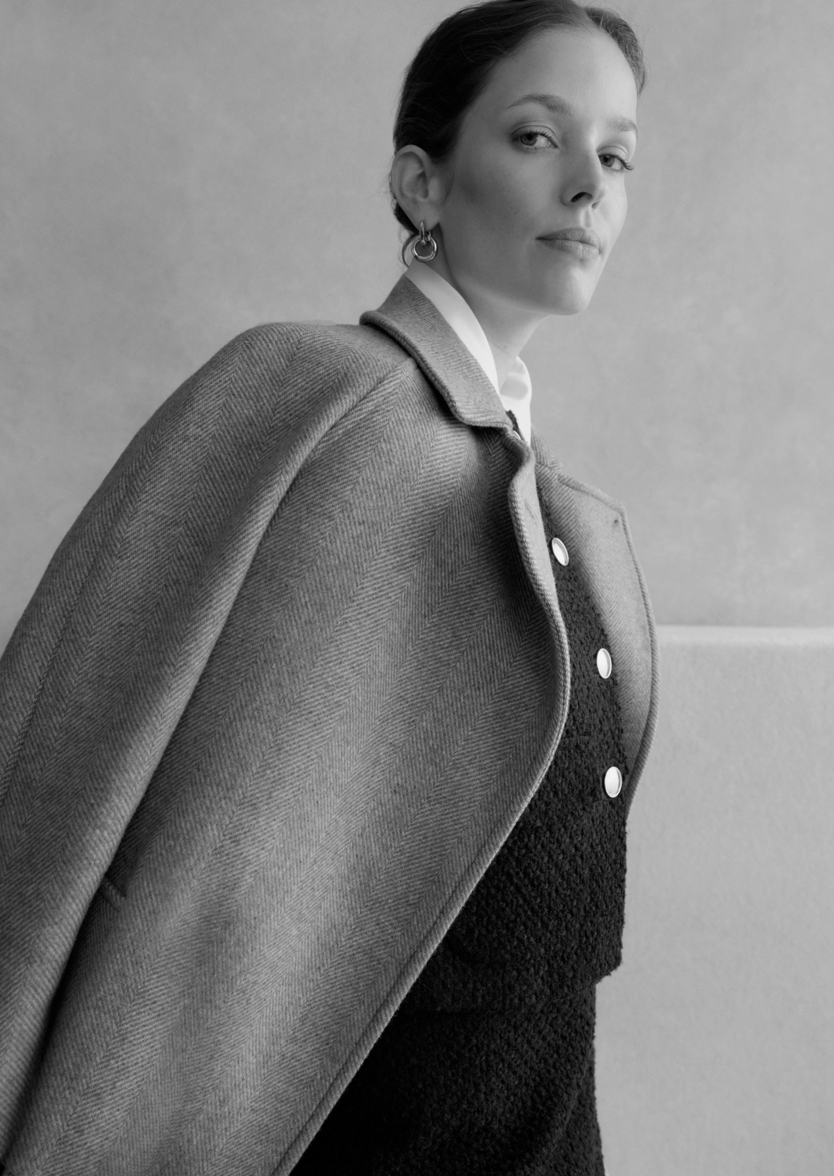 A gallery of two images displaying a model wearing a beige tailored coat.