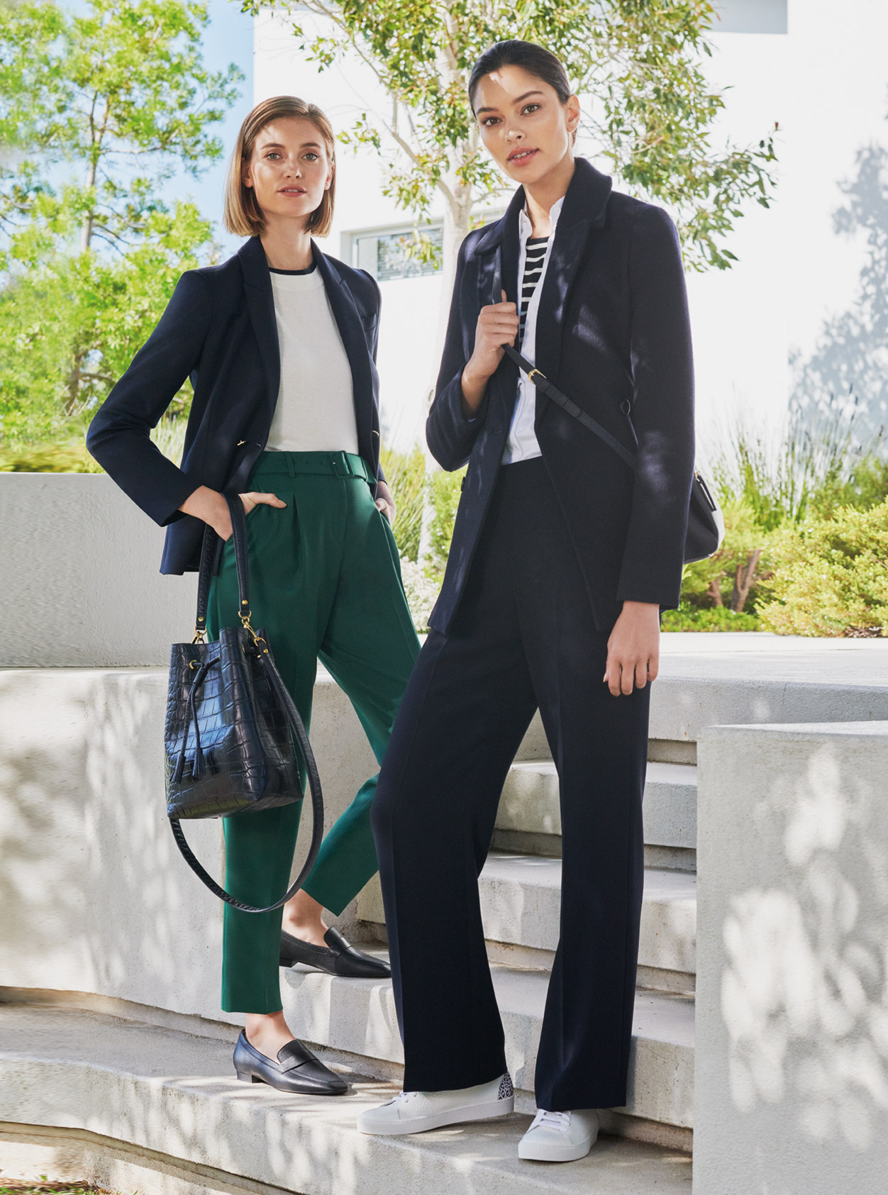 Women’s trouser suit outfits, the outfit on the left pairs the suit with a white top, green tailored trousers, black loafers and a black leather tote bag. The outfit on the right pairs the suit with a stripey top, a black crossbody bag, wide leg trousers and white trainers, all from Hobbs.