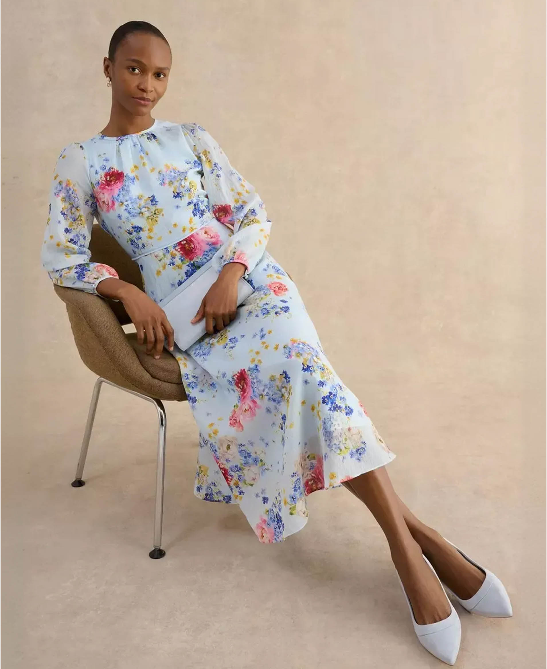 A woman wearing a pale blue, floral, occasion dress.