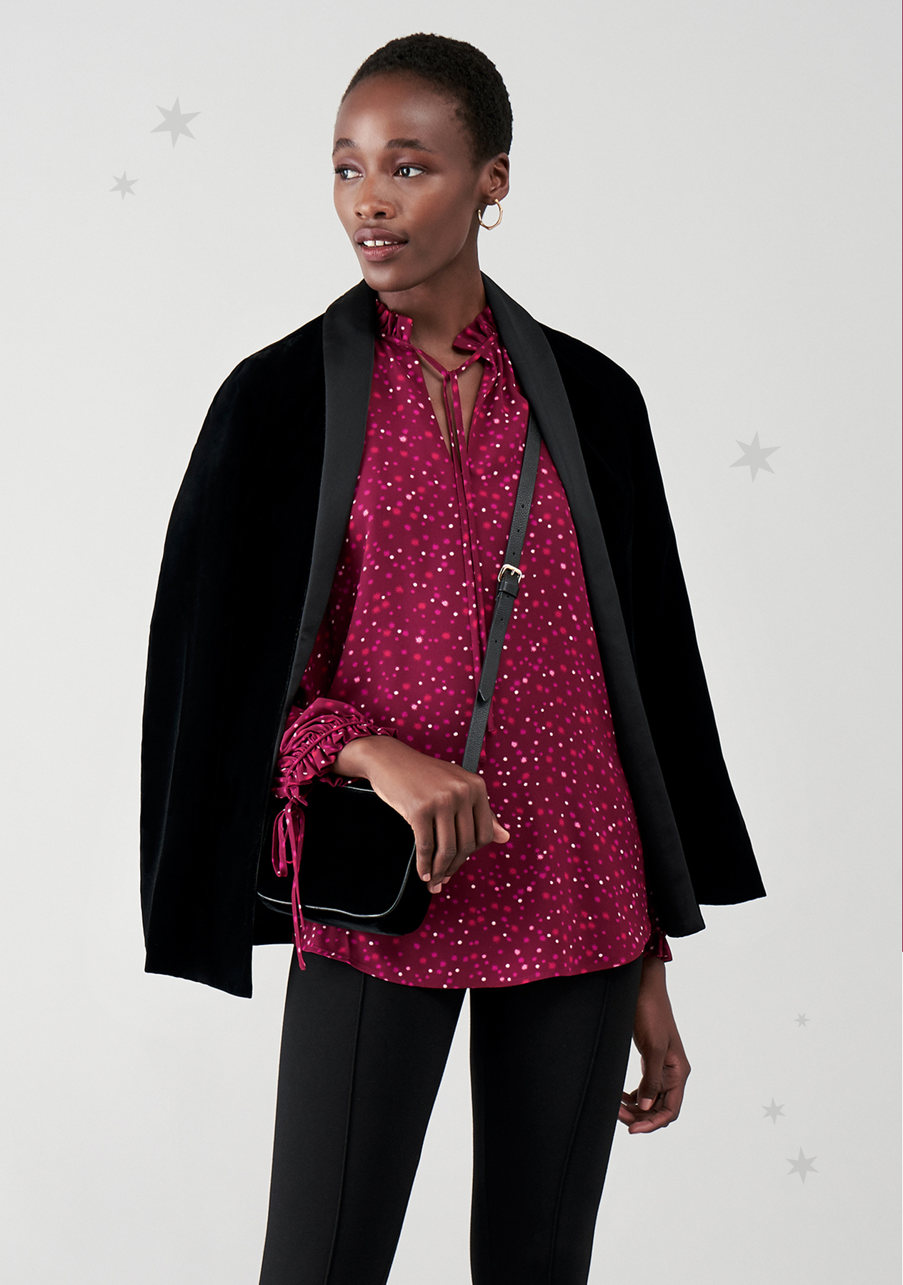Model wears a star print dress with embellished shoes and a metallic clutch bag.
