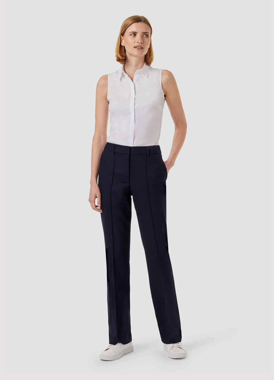  Sleeveless work blouse in white worn with black straight leg trousers and white trainers from Hobbs.
