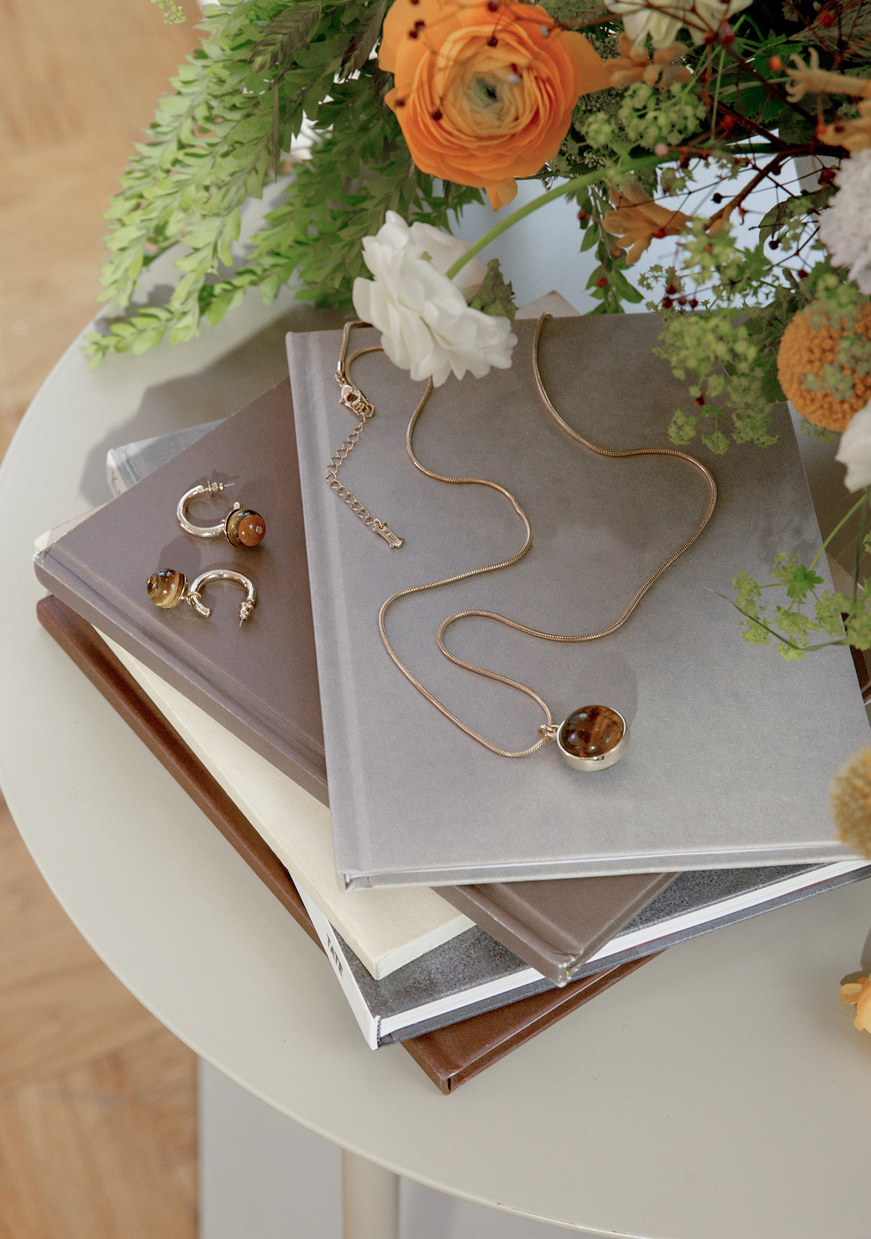 Table displaying a vase of flowers and Hobbs jewellery arranged on a pile of books.