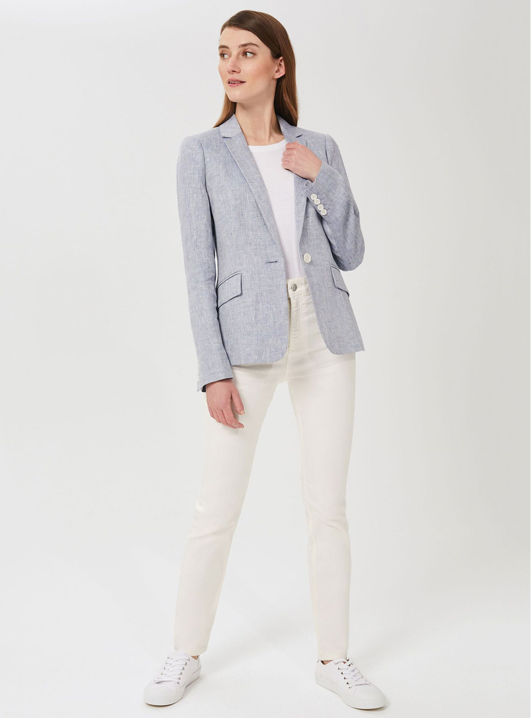 Model wears white jeans and a blue linen blazer.