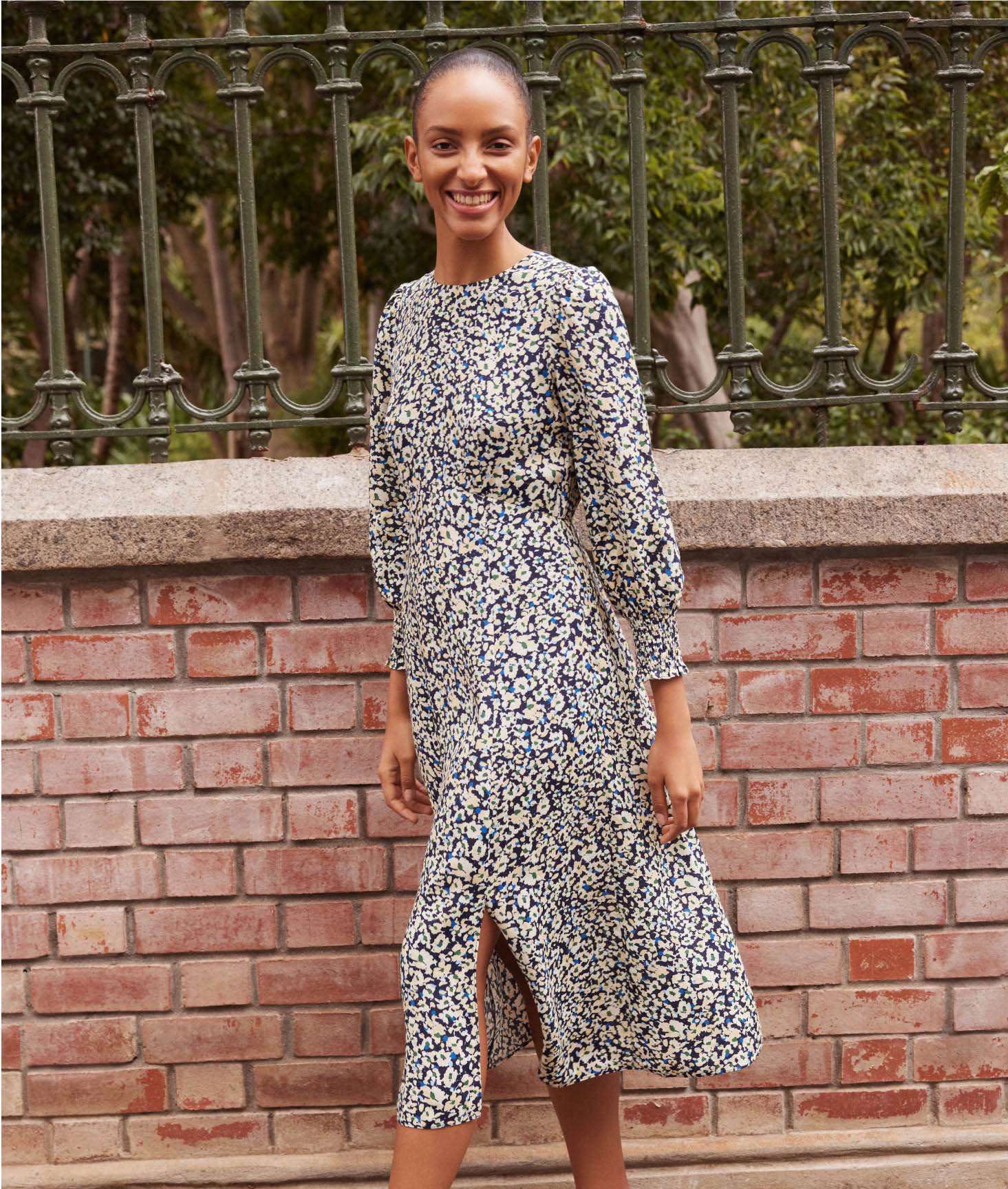 Photo of model walking down a street wearing a floral midi dress.