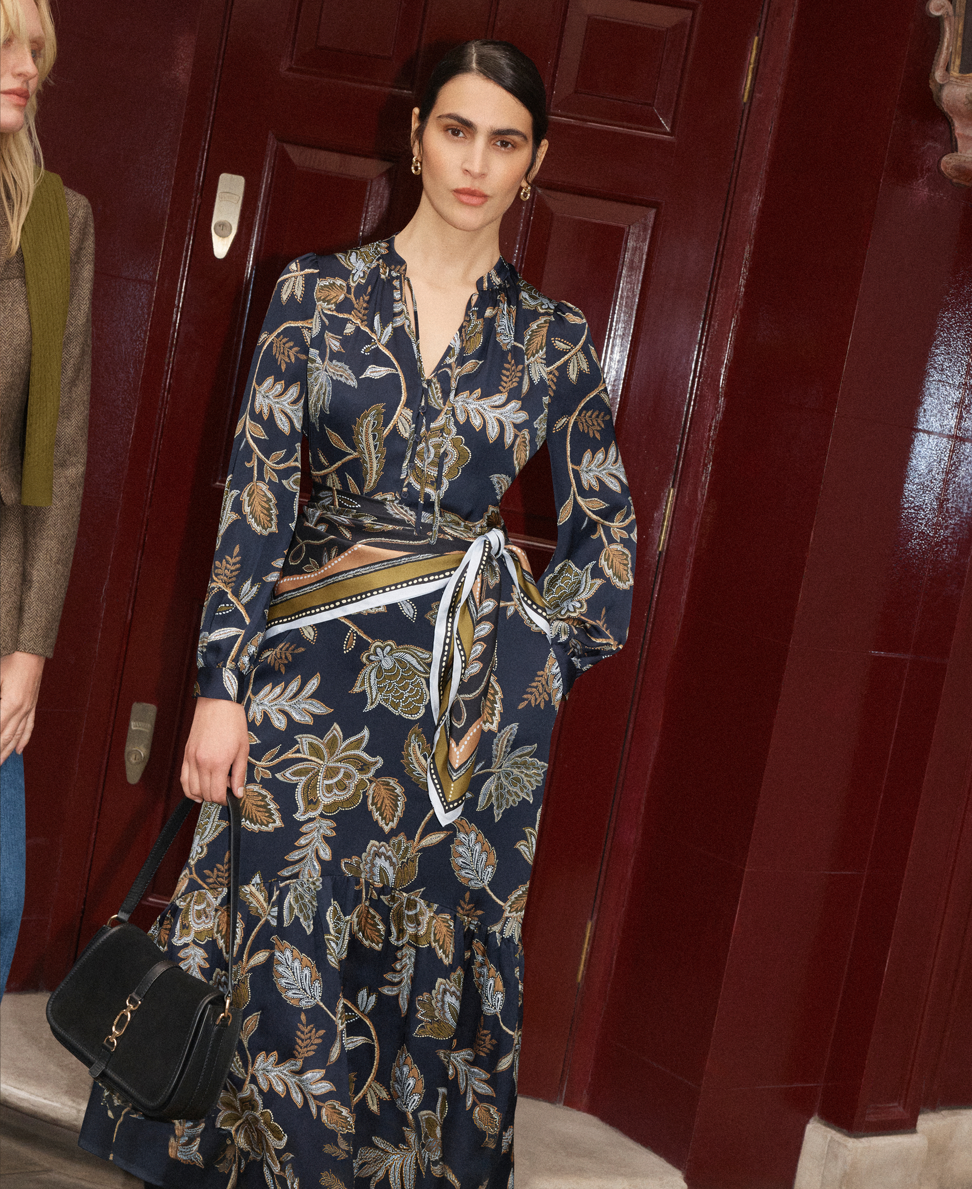 A woman wearing a Hobbs printed dress and trench coat.