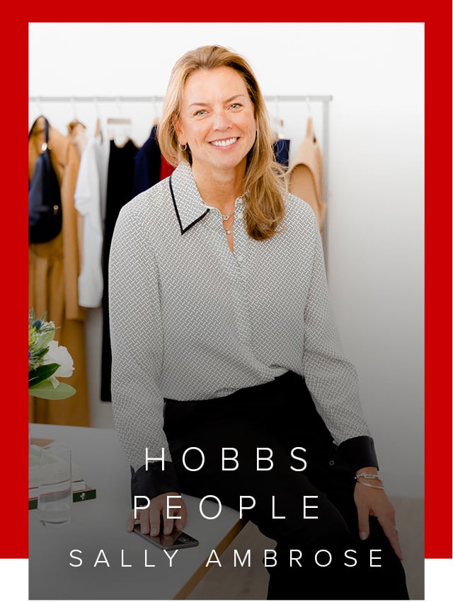  Hobbs' Product Director, Sally Ambrose, photographed wearing a silk shirt while leaning on an office desk.