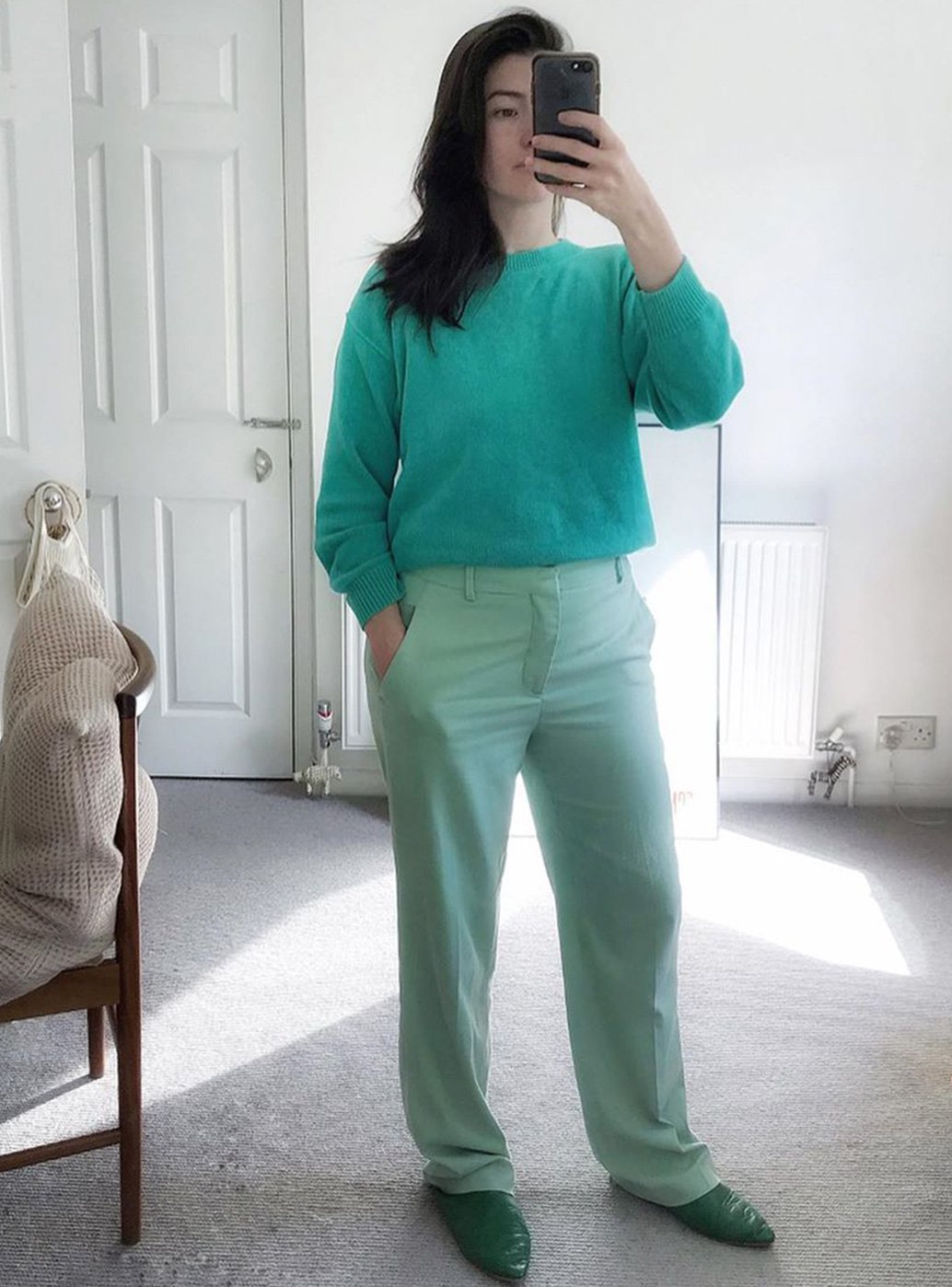 Brand stylist Maddy Moxham takes a selfie  dressed in a serene green outfit at home