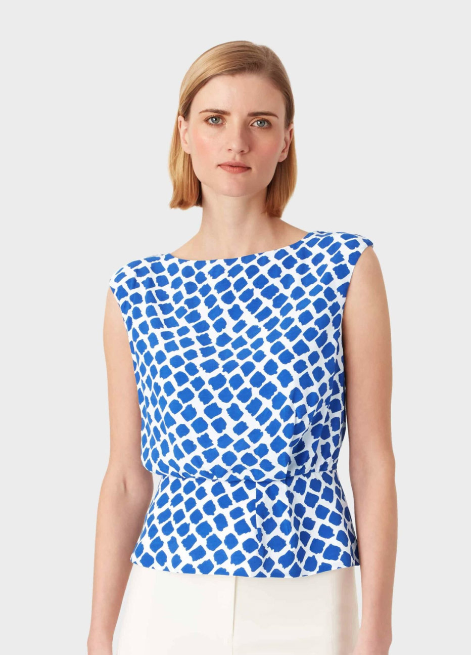 Women’s top in blue and white with a contemporary spot print styled with white trousers, by Hobbs.