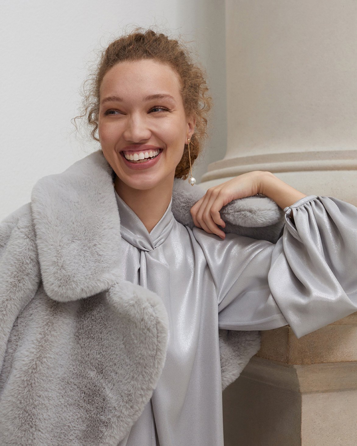 Hobbs models wears a metallic silver dress and faux fur coat.