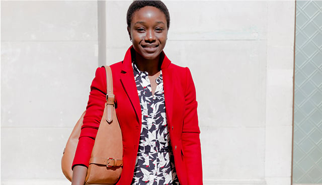 Model photographed wearing a green satin blouse with black trousers and a clutch bag from Hobbs.