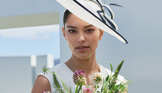White fascinator with navy blue details, worn with a white dress by Hobbs.