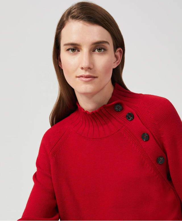 Model photographed wearing a red sweater with button detailing.