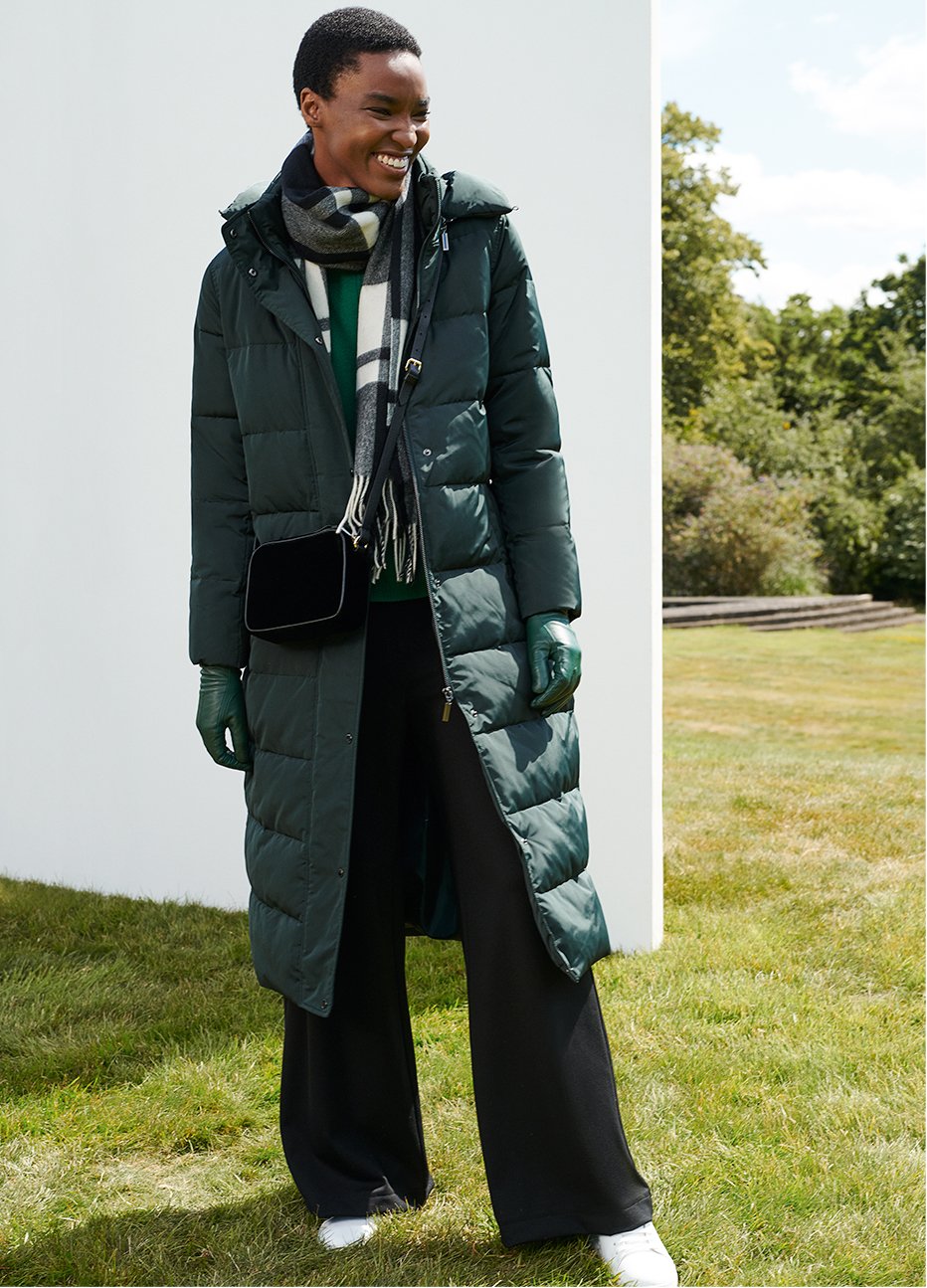 Full length image of model wearing a puffer coat and checked scarf.