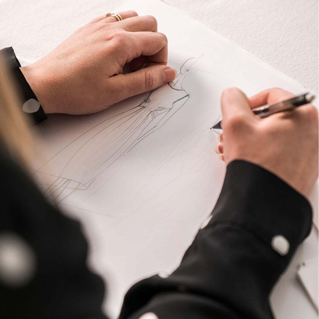 Photograph closely showing a Hobbs womenswear designer sketching clothing.