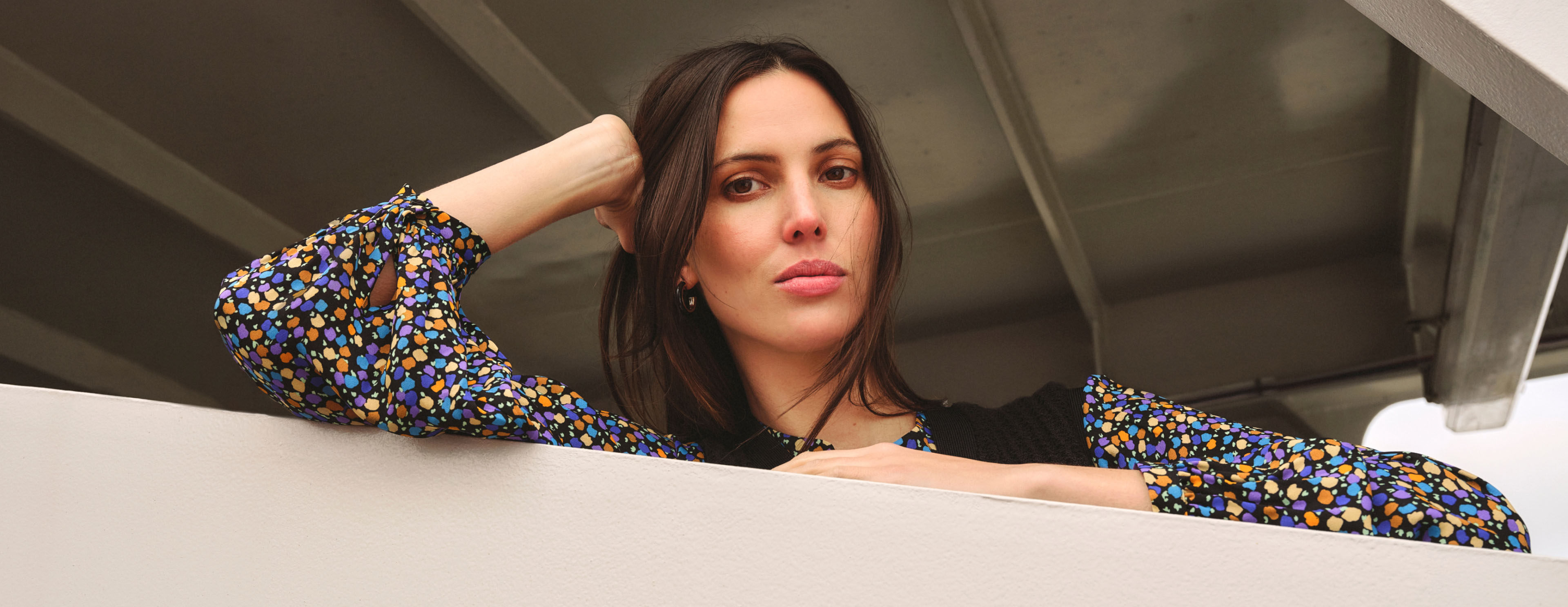 Model photographed in knitted vest and patterned blouse.