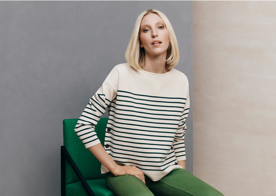 Model photographed sitting in a chair wearing green denim jeans.