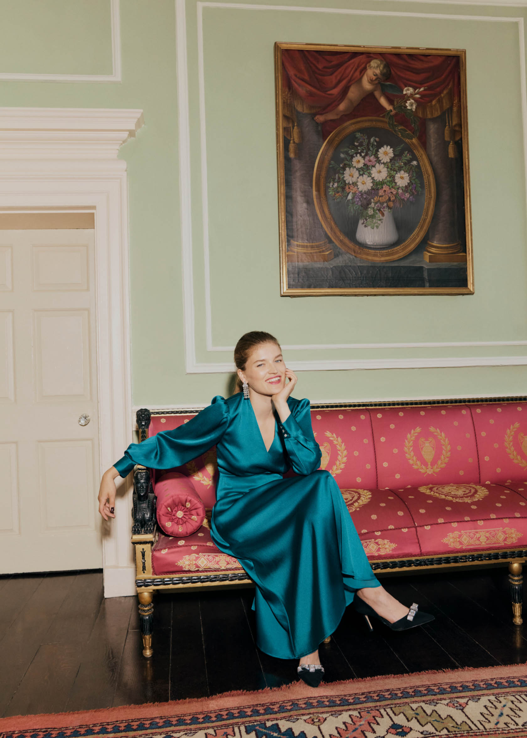 Image of a model sitting on a sofa wearing a party dress.