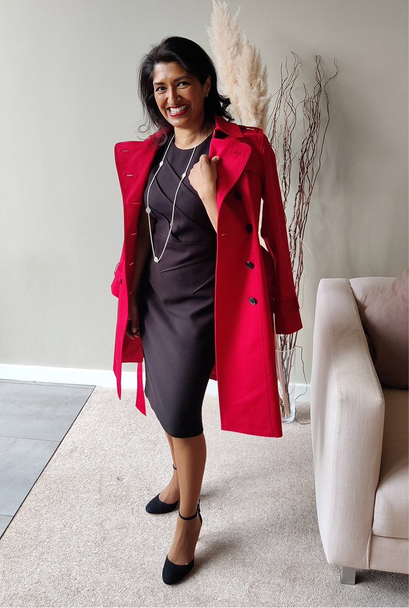 Photographed at home, fashion blogger Monika Manda wears Hobbs petite red Saskia trench over the Ophelia black dress.