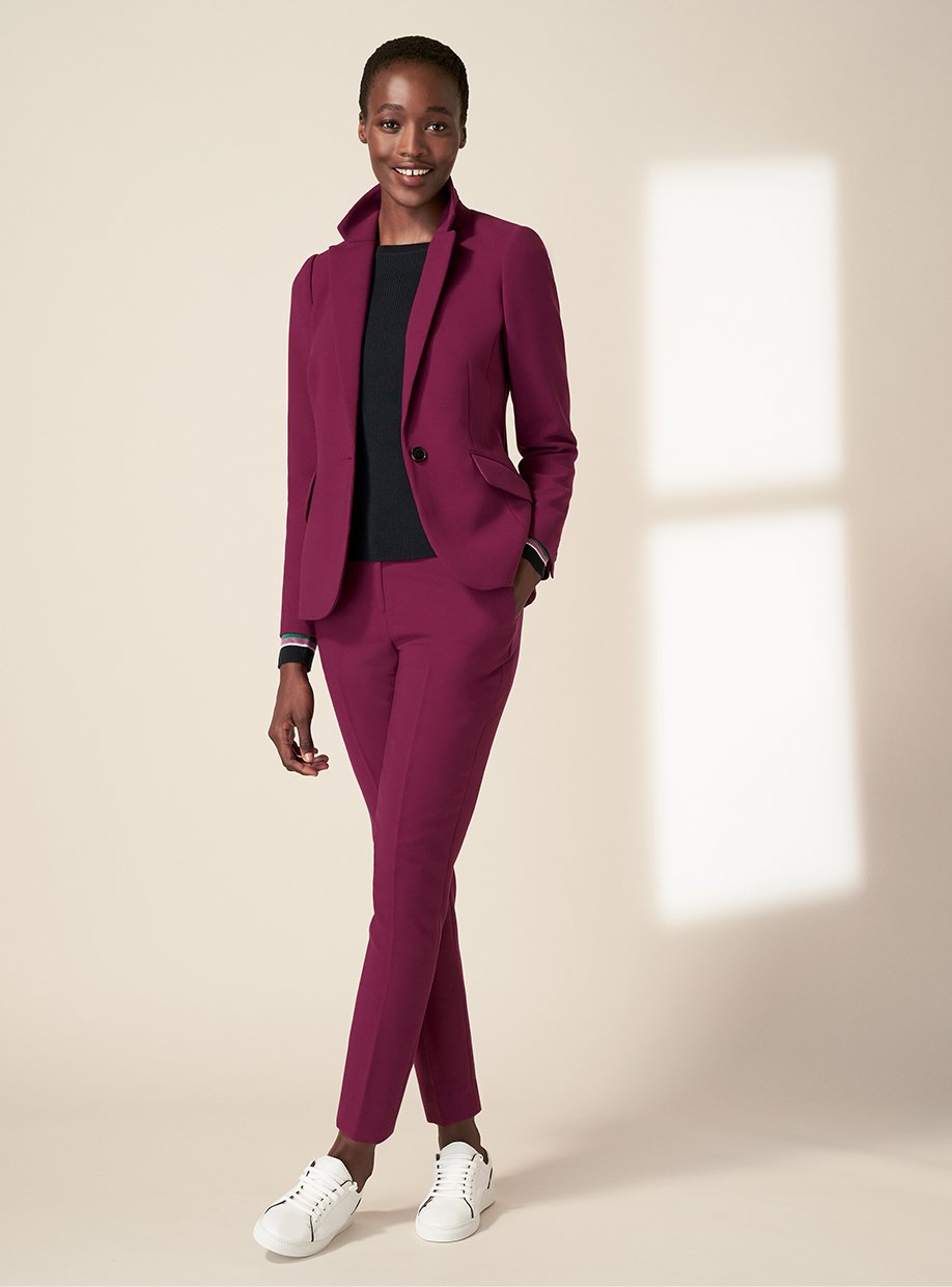 Model wearing Hobbs' Suki magenta pink tailored jacket and matching trousers with trainers.