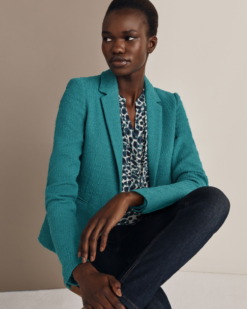 Hobbs model wears a green blazer with a leopard print blouse and jeans.