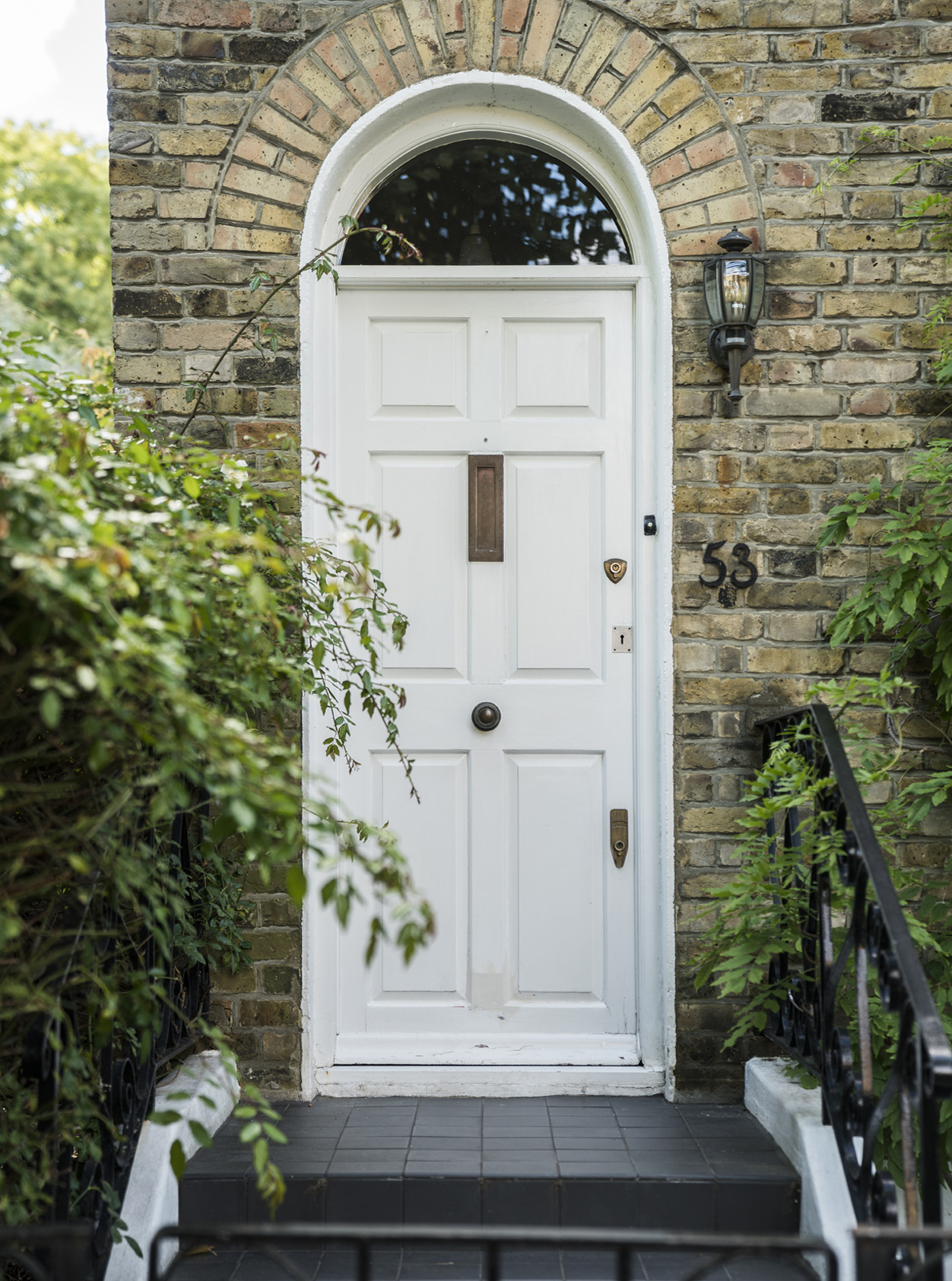 A classic hampstead townhouse frontage with a white front door, with surrounding greenery.