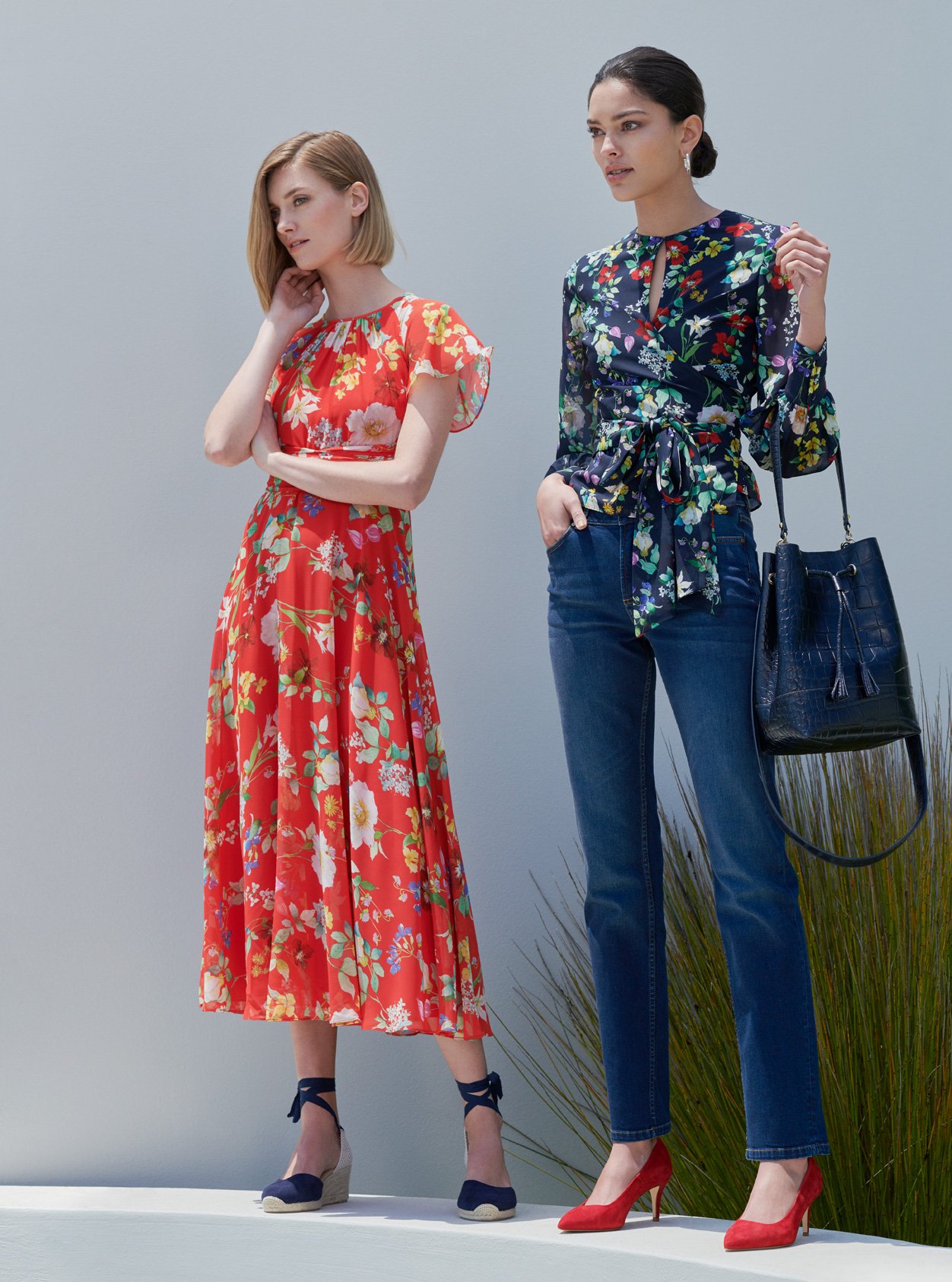 Red floral midi dress with espadrille wedge heels and a floral wrap blouse paired with blue denim jean, red court shoes and a leather bucket bag by Hobbs.