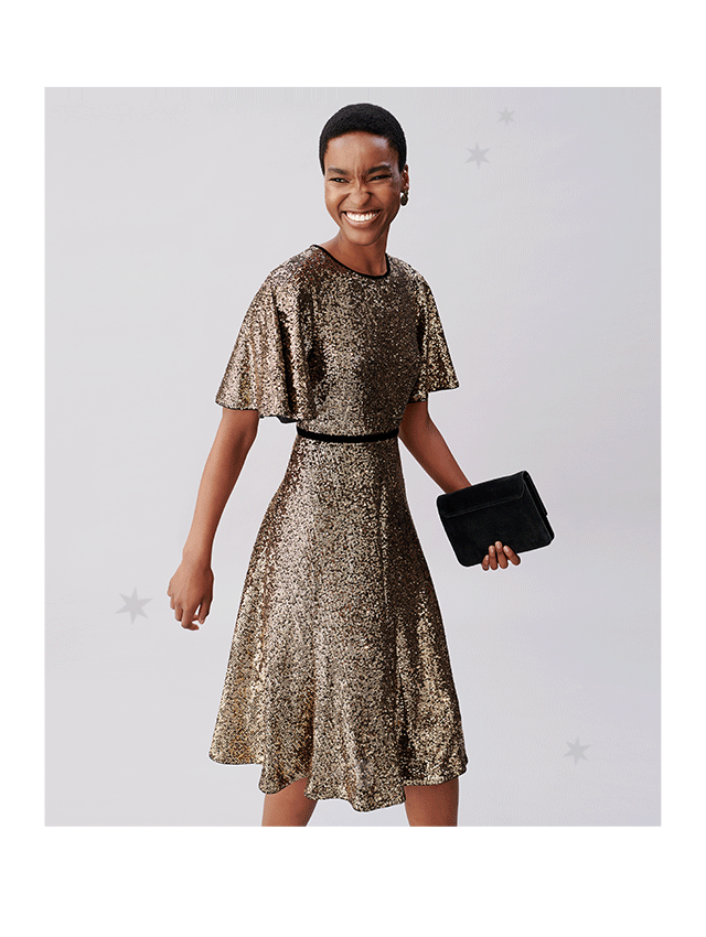 Model wears a sequin dress and holds a clutch bag from Hobbs.