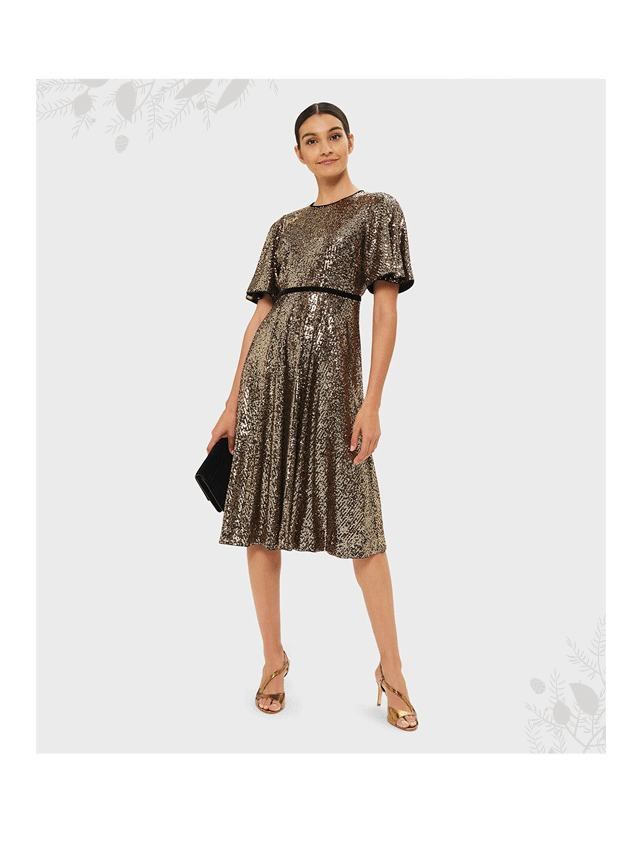 Model wears a gold sequinned fit and flare dress with bronze metallic heeled sandals from Hobbs.