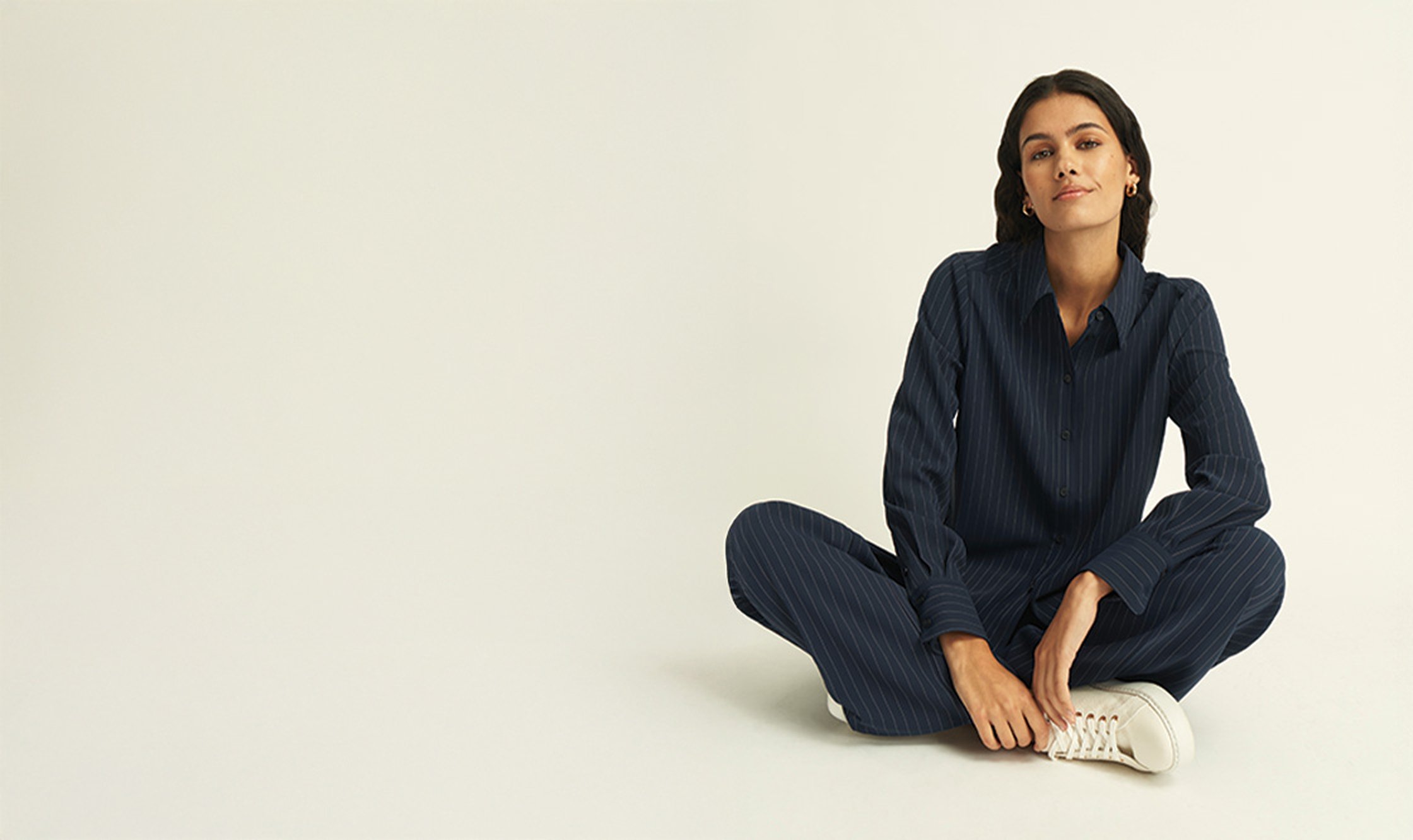 A girl sat down wearing a navy pinstripe shirt and coordinating trousers.